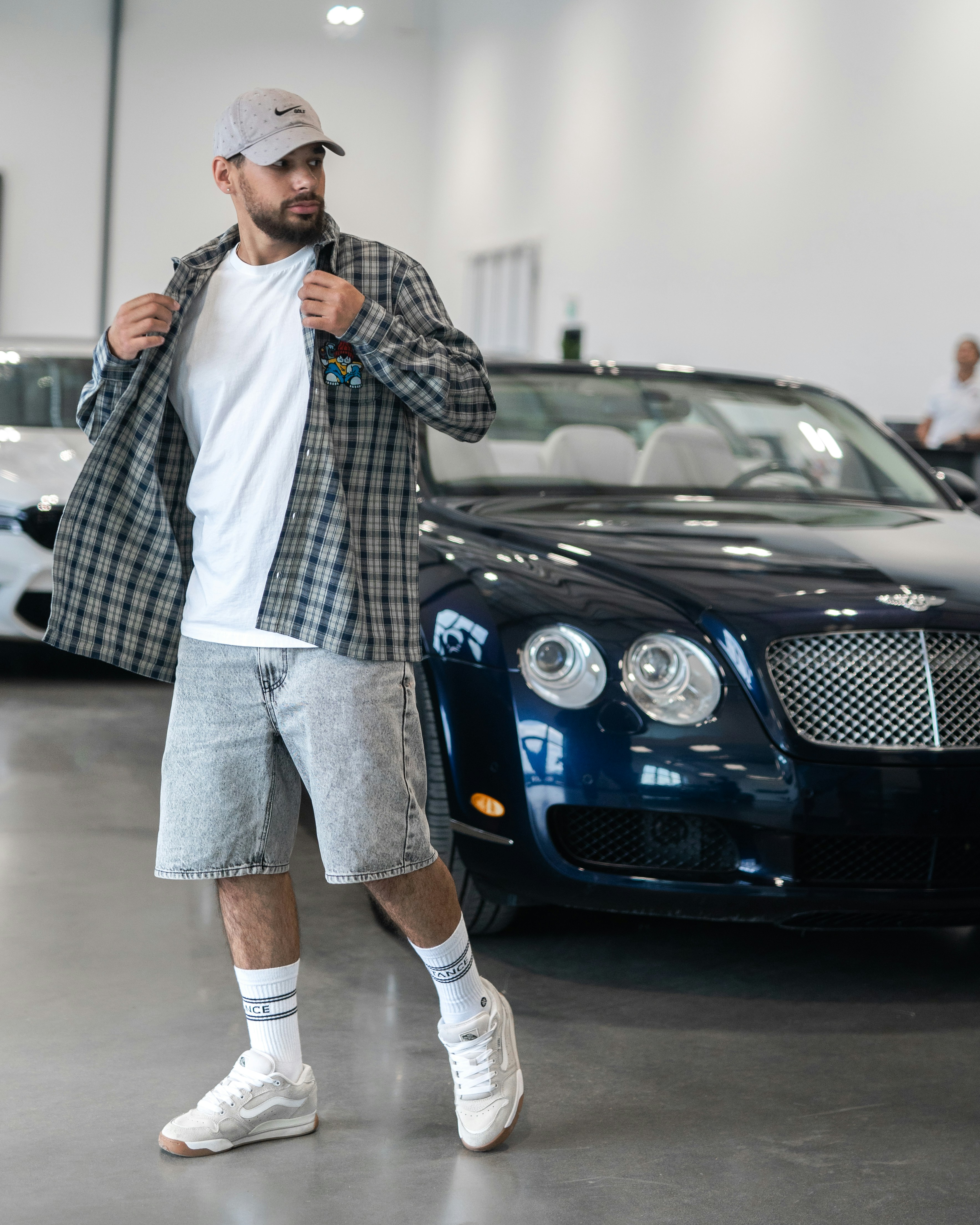 Man stands near a car, posing with style.
