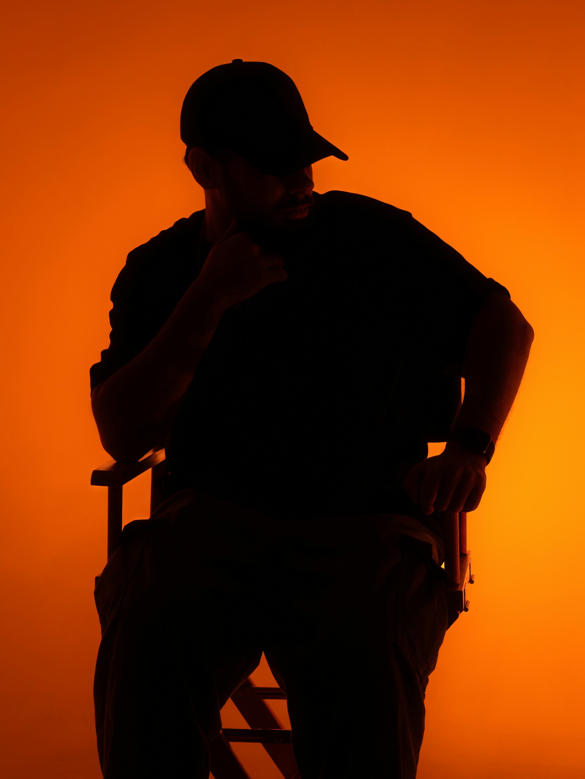 A man sits silhouetted against an orange background.