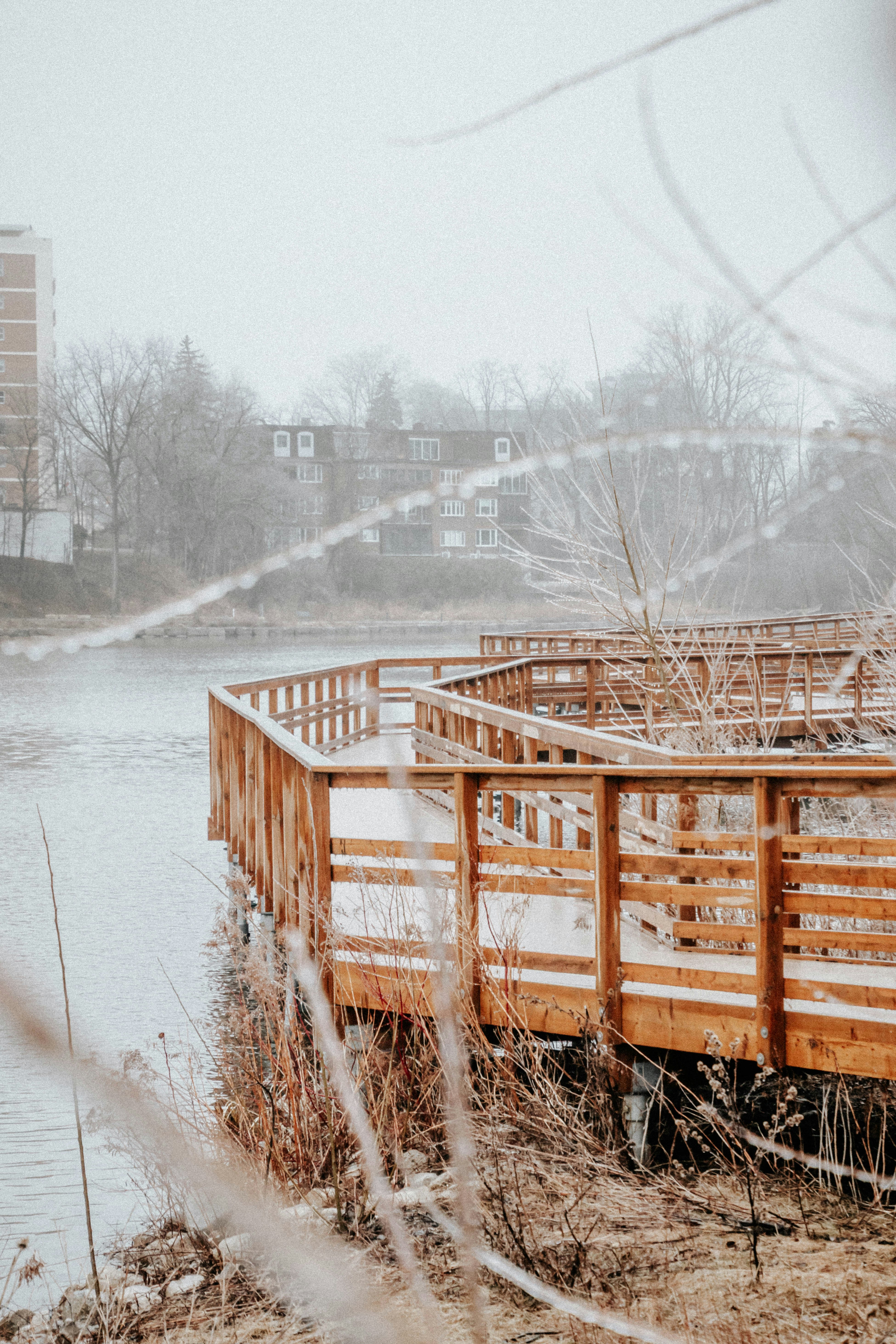Wooden walkway sits by a body of water in winter.
