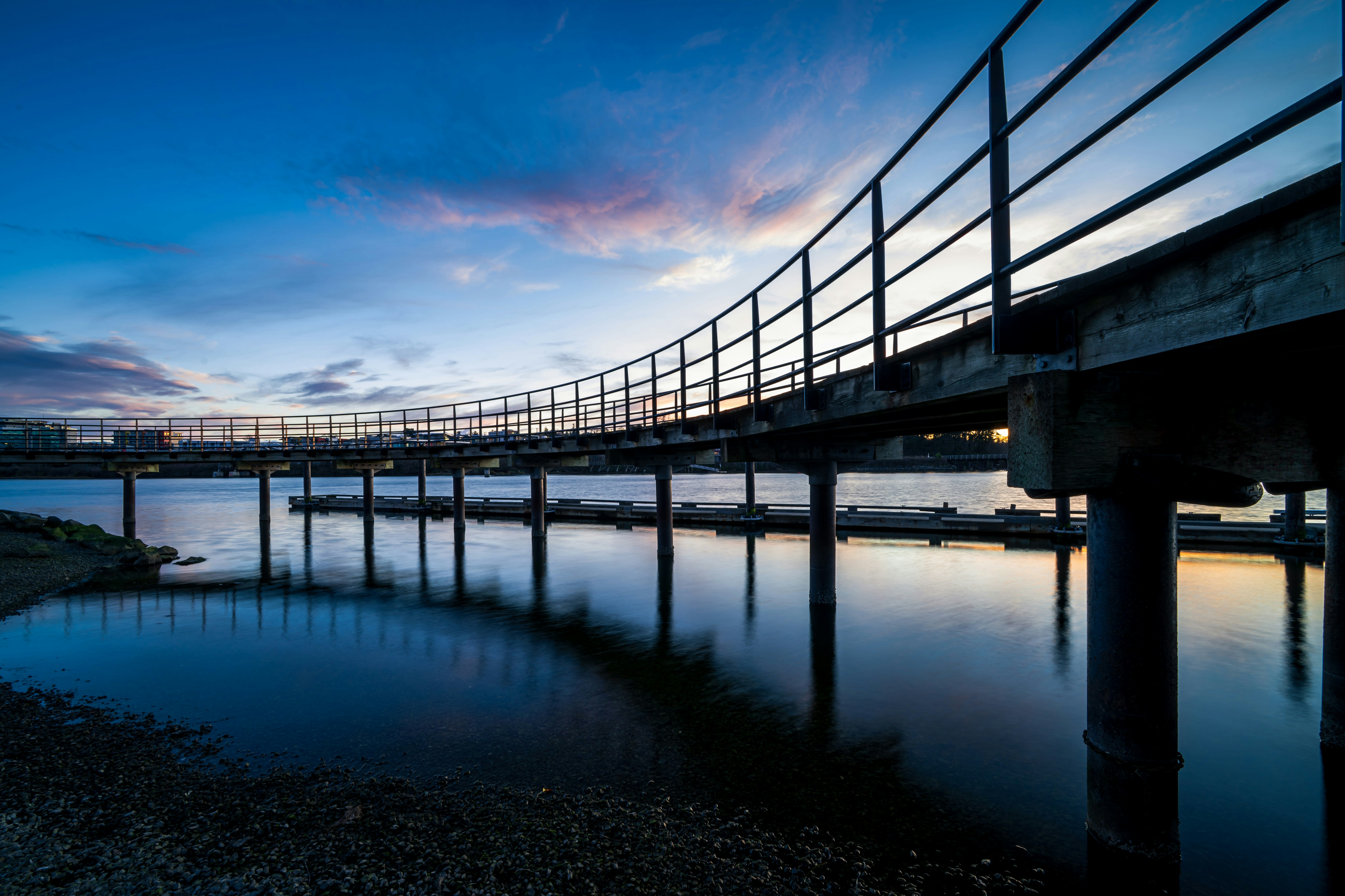 Bridge over calm water during a colorful sunset.