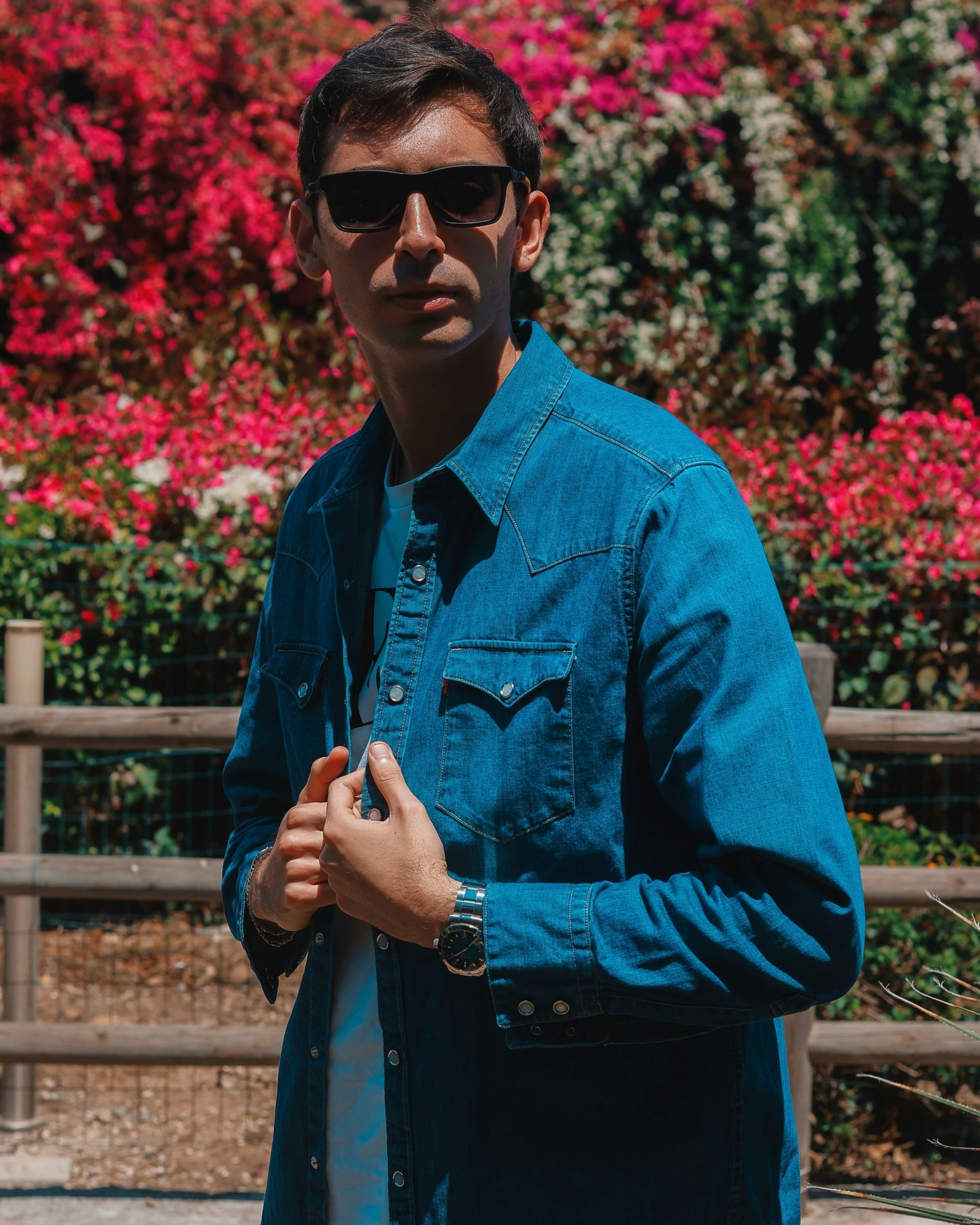 Ein Mann mit Sonnenbrille posiert draußen.