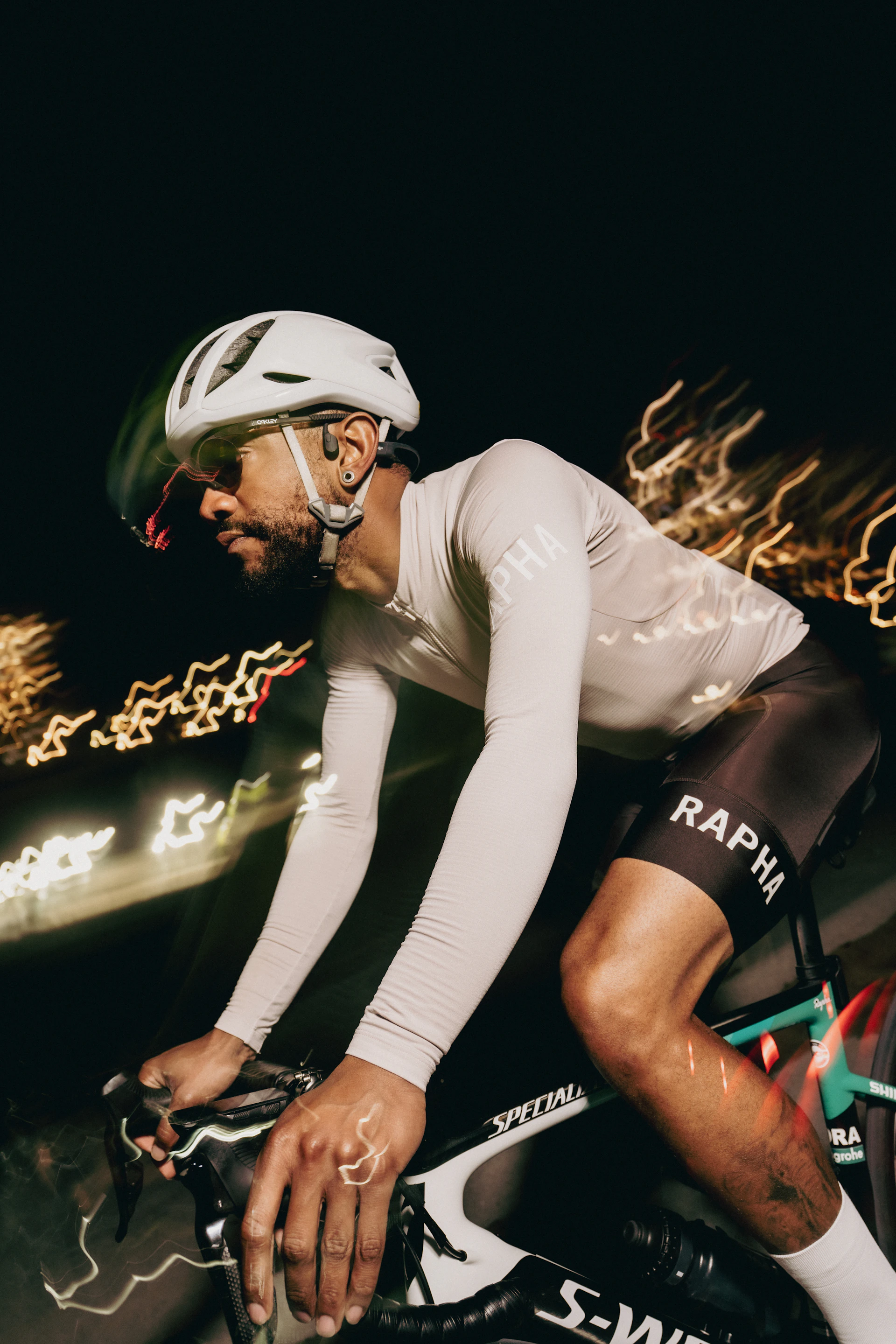 Cyclist rides through the night with blurred lights.