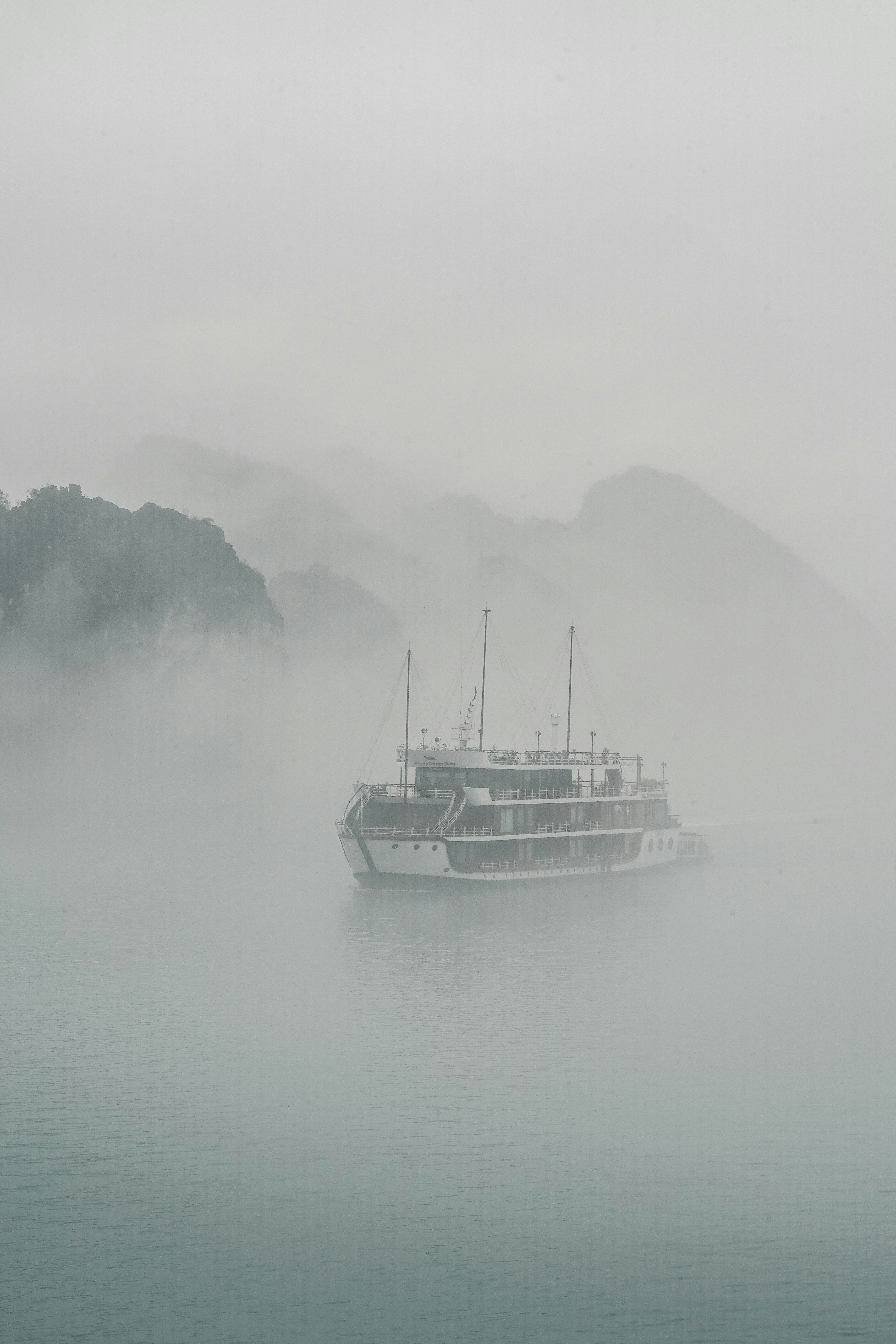 A boat sails through the foggy waters.