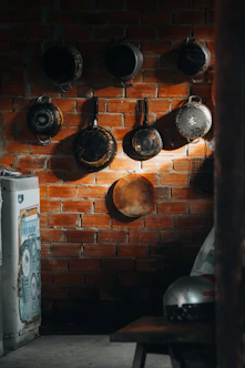 Pots and pans hang on a brick wall.