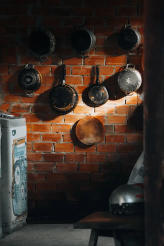 Pots and pans hang on a brick wall.