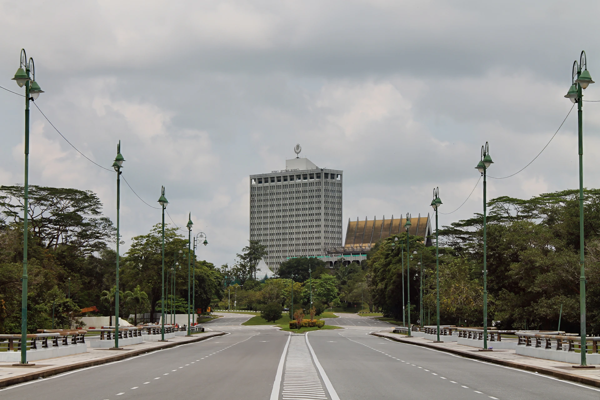 A wide road leads to a tall building.