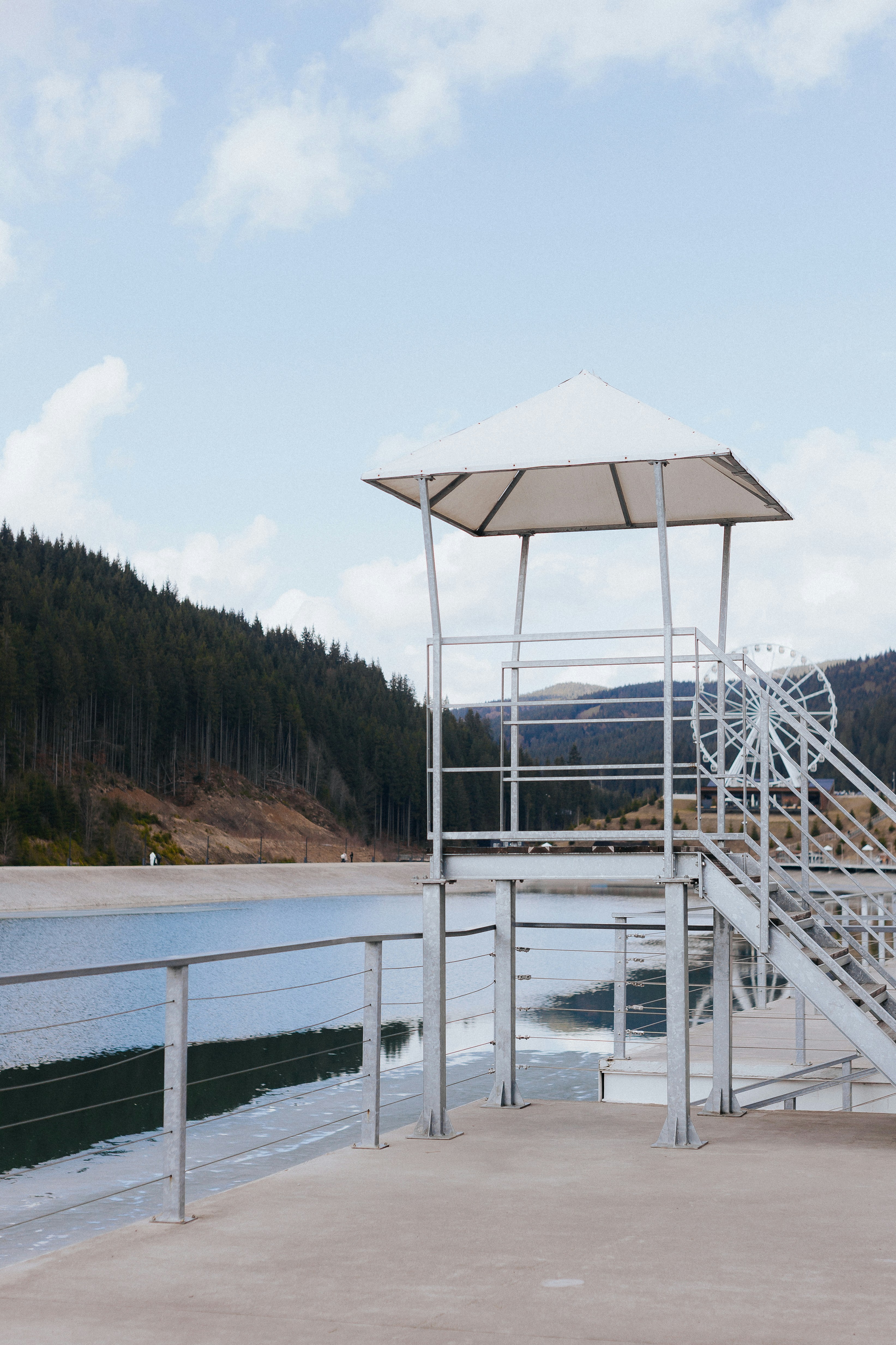 A white structure overlooks a still lake.