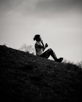 Woman sits on a hill, seemingly deep in thought.