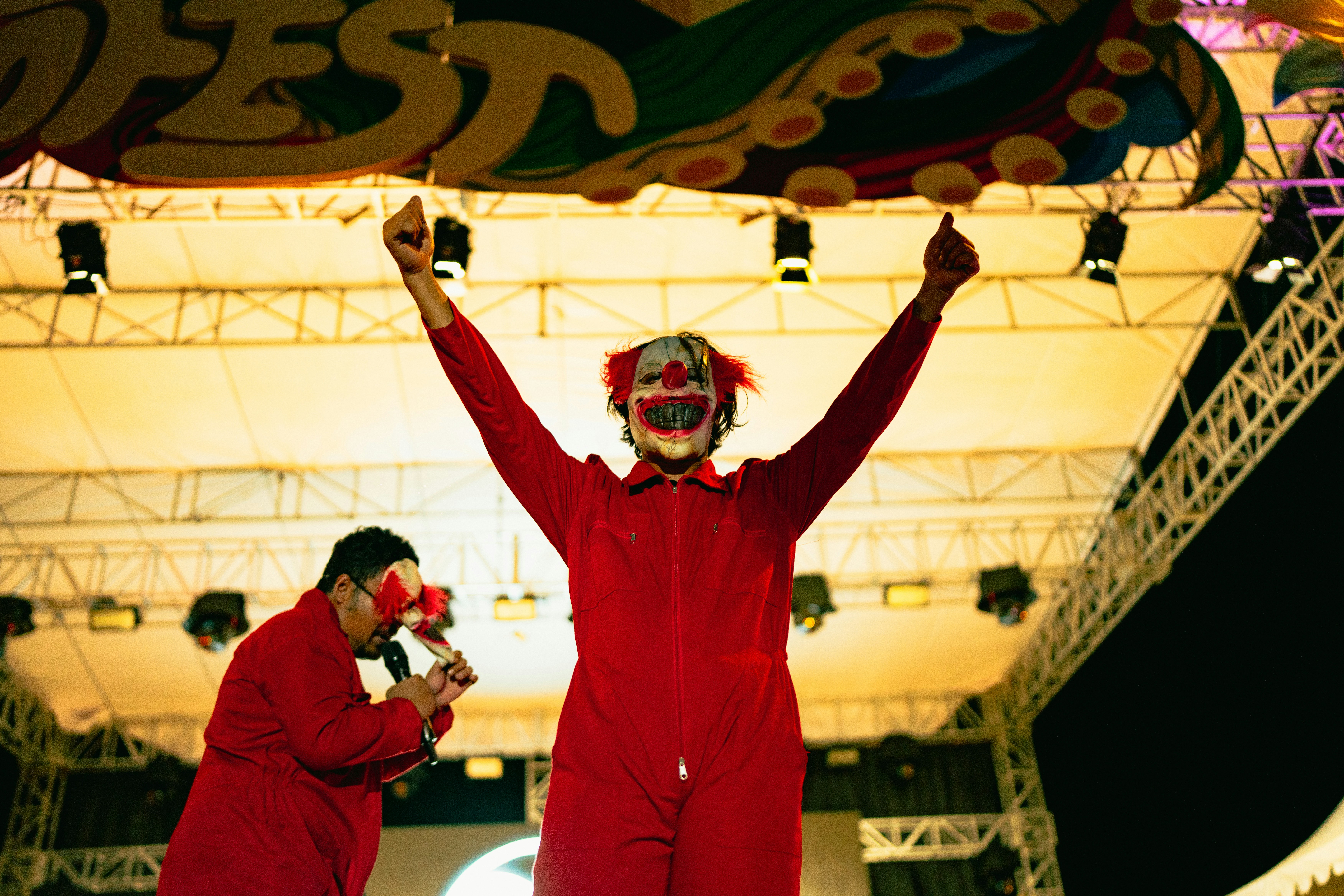 Seorang badut dengan jumpsuit merah di atas panggung.