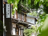 Japanese shop exterior is seen through the leaves.