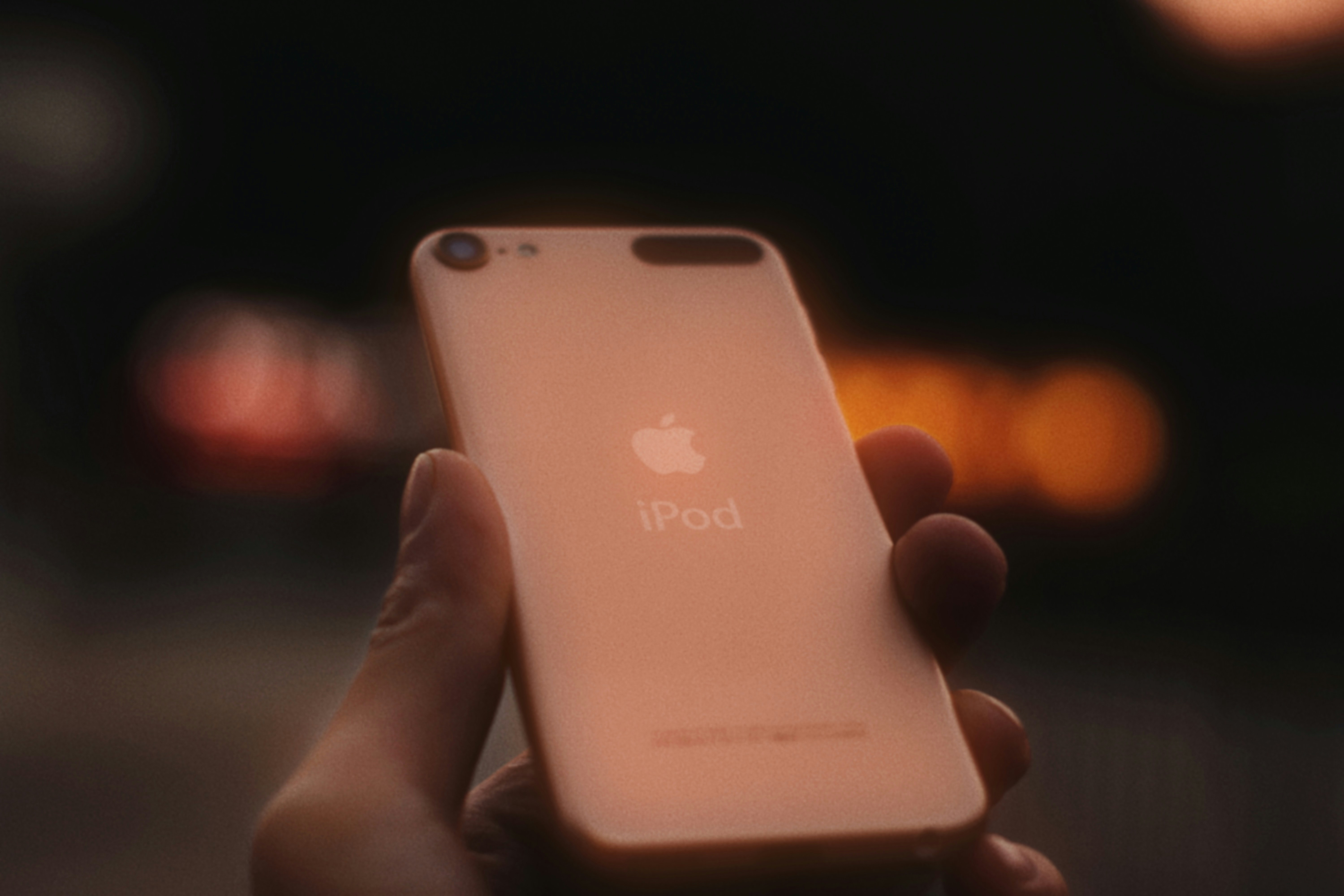 Hand holding a pink apple iPod touch.