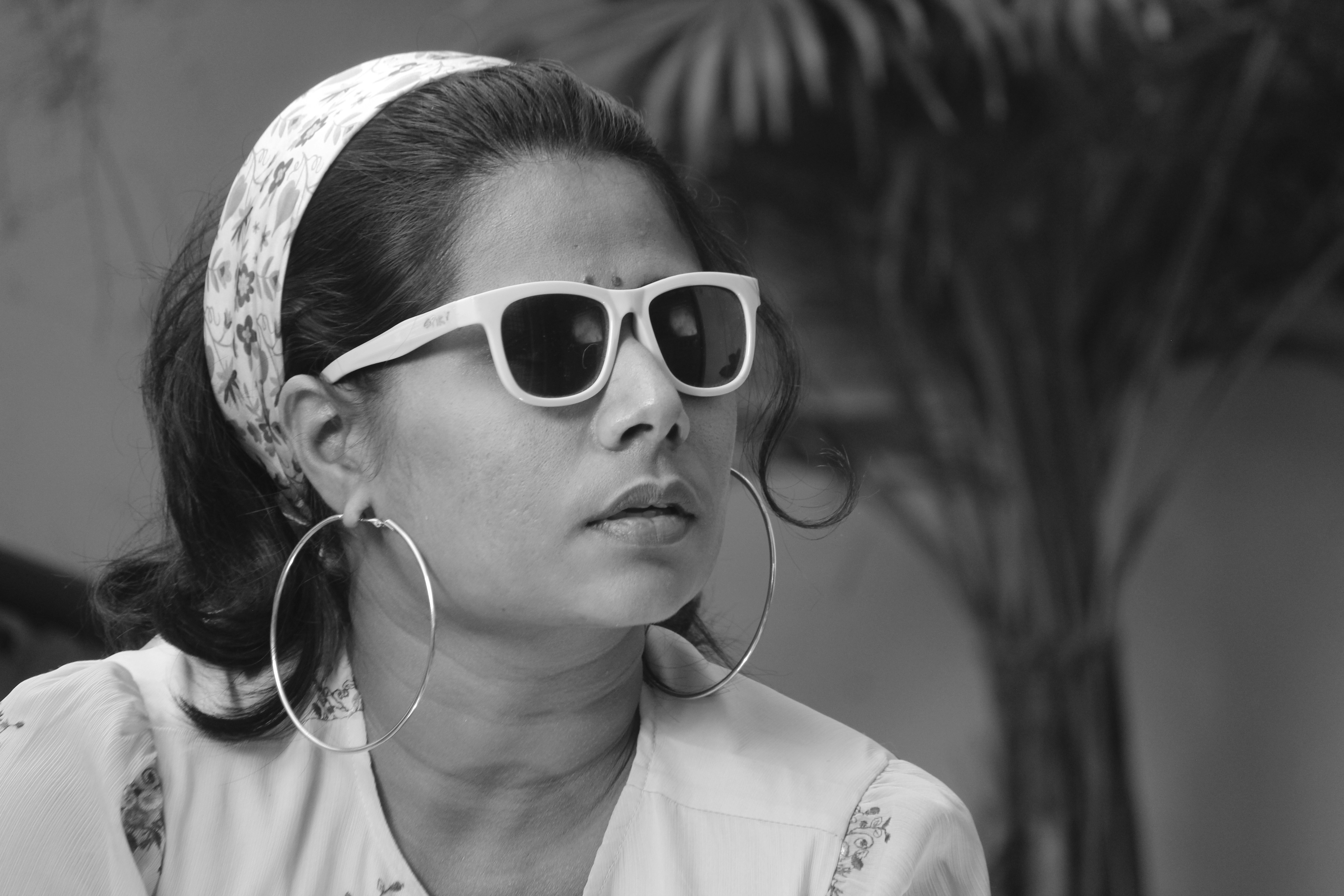 Woman wears sunglasses and hoop earrings.