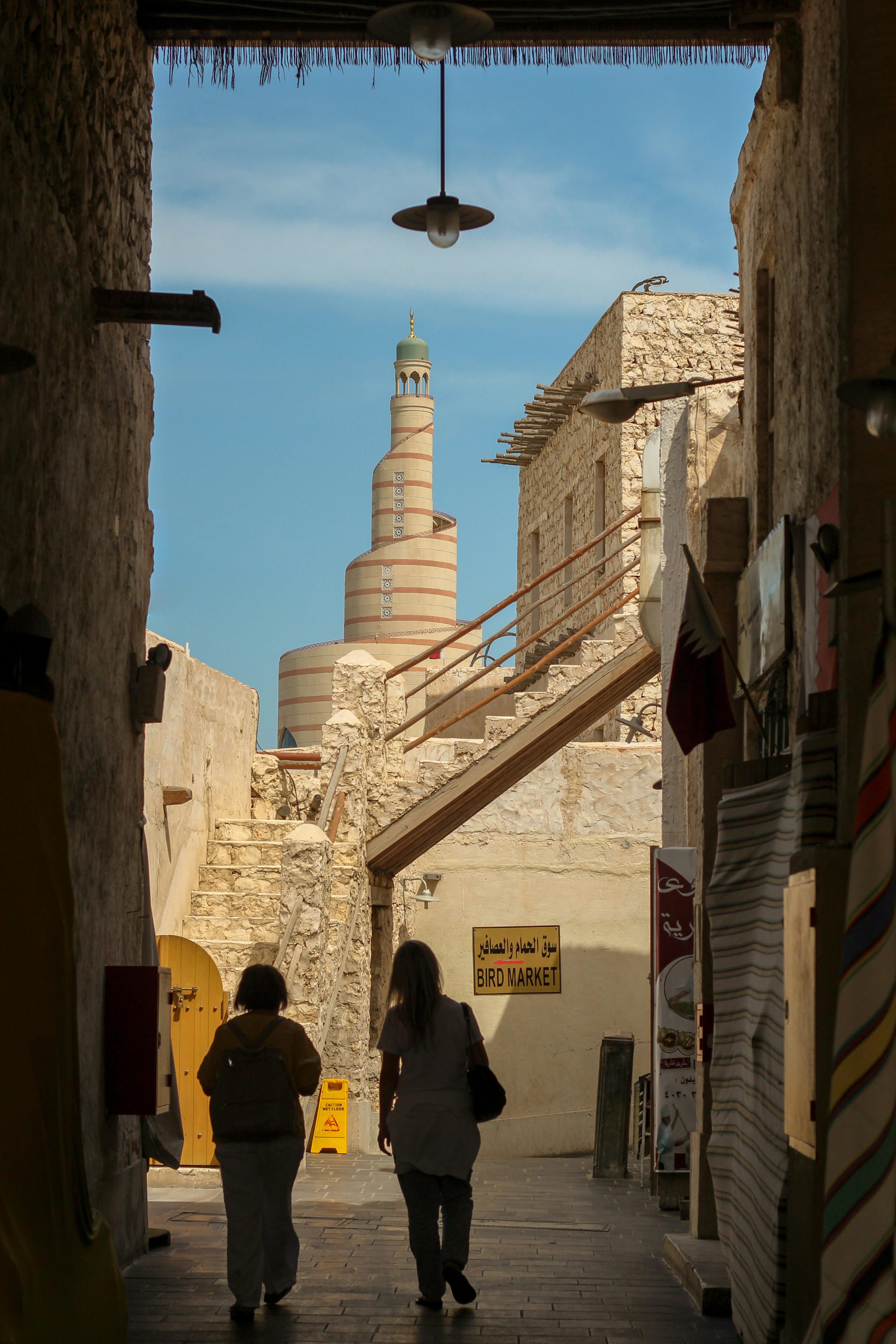 People walk through a street towards a tower.