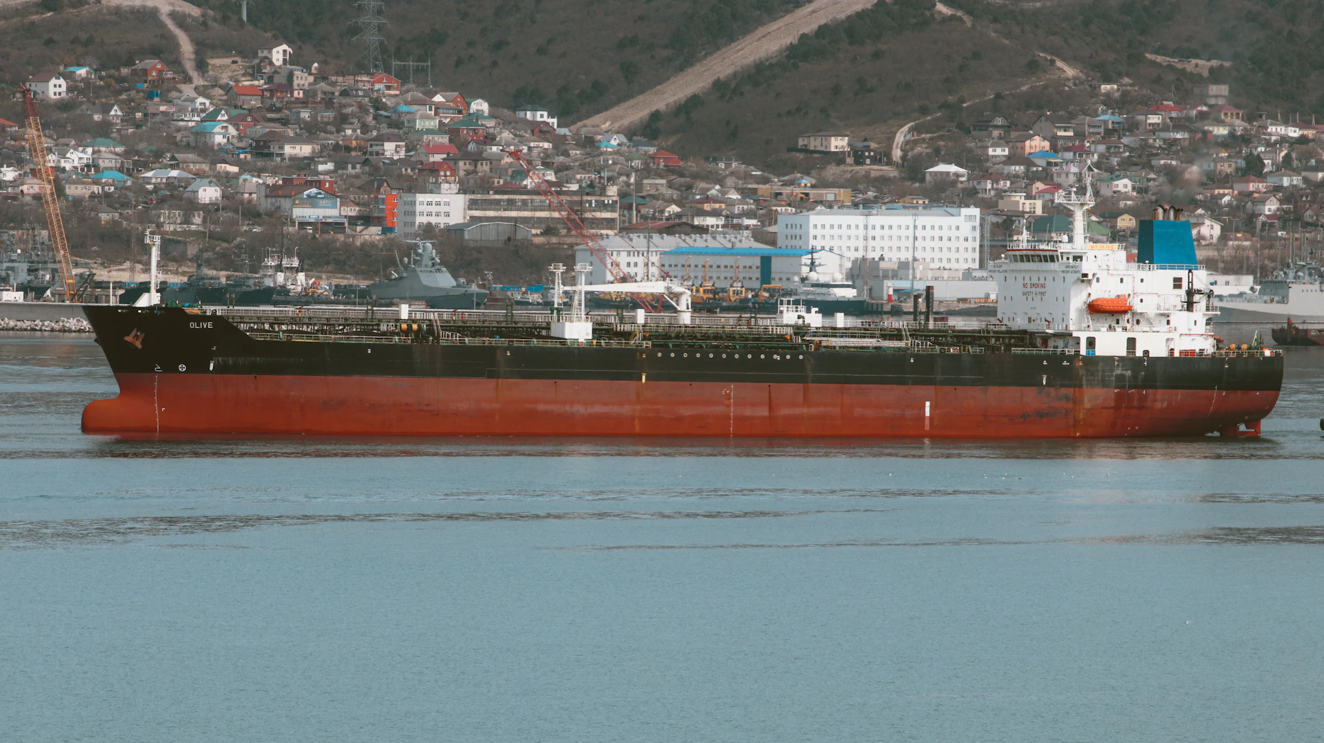 A large oil tanker floats near a city