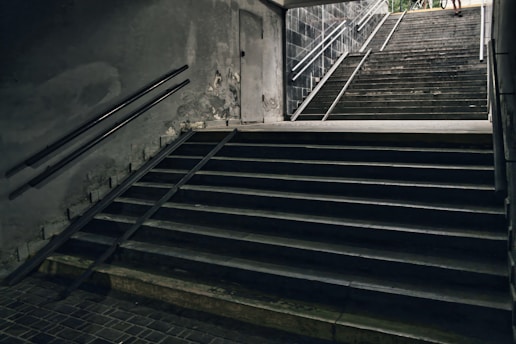 Stairways descend into the darkness of an underpass.