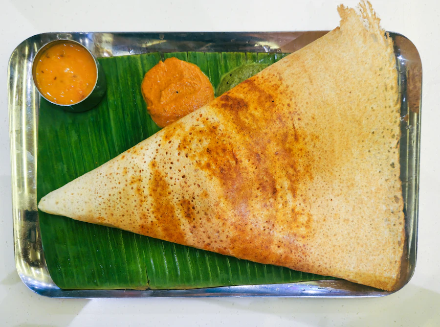 A golden, crisp masala dosa served with sambar and coconut chutney on a plate