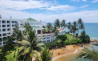 Beachside hotel with palm trees under a blue sky.