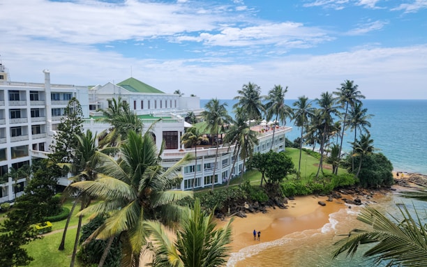 Beachside hotel with palm trees under a blue sky.