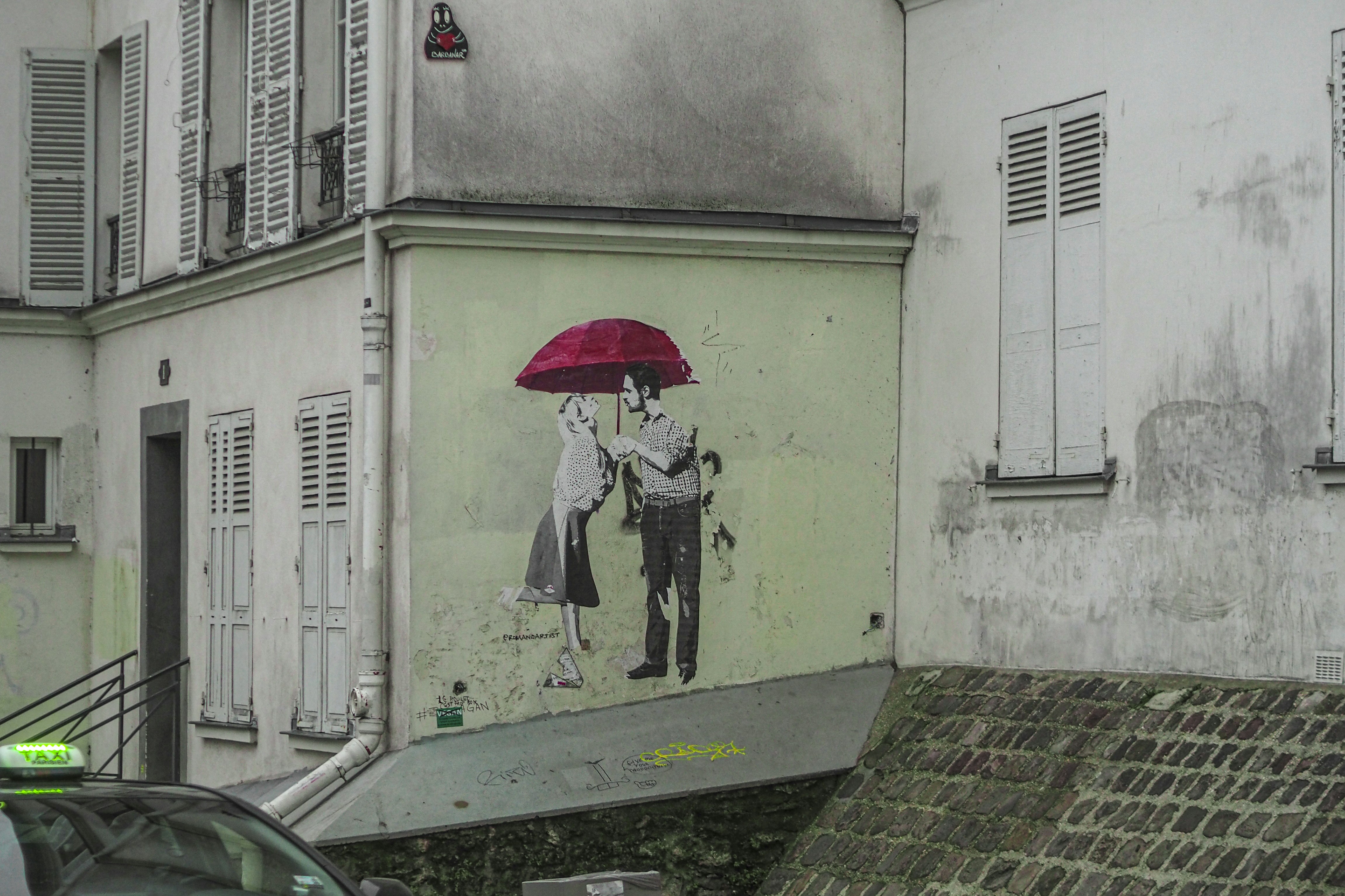 A couple is embracing under a red umbrella.
