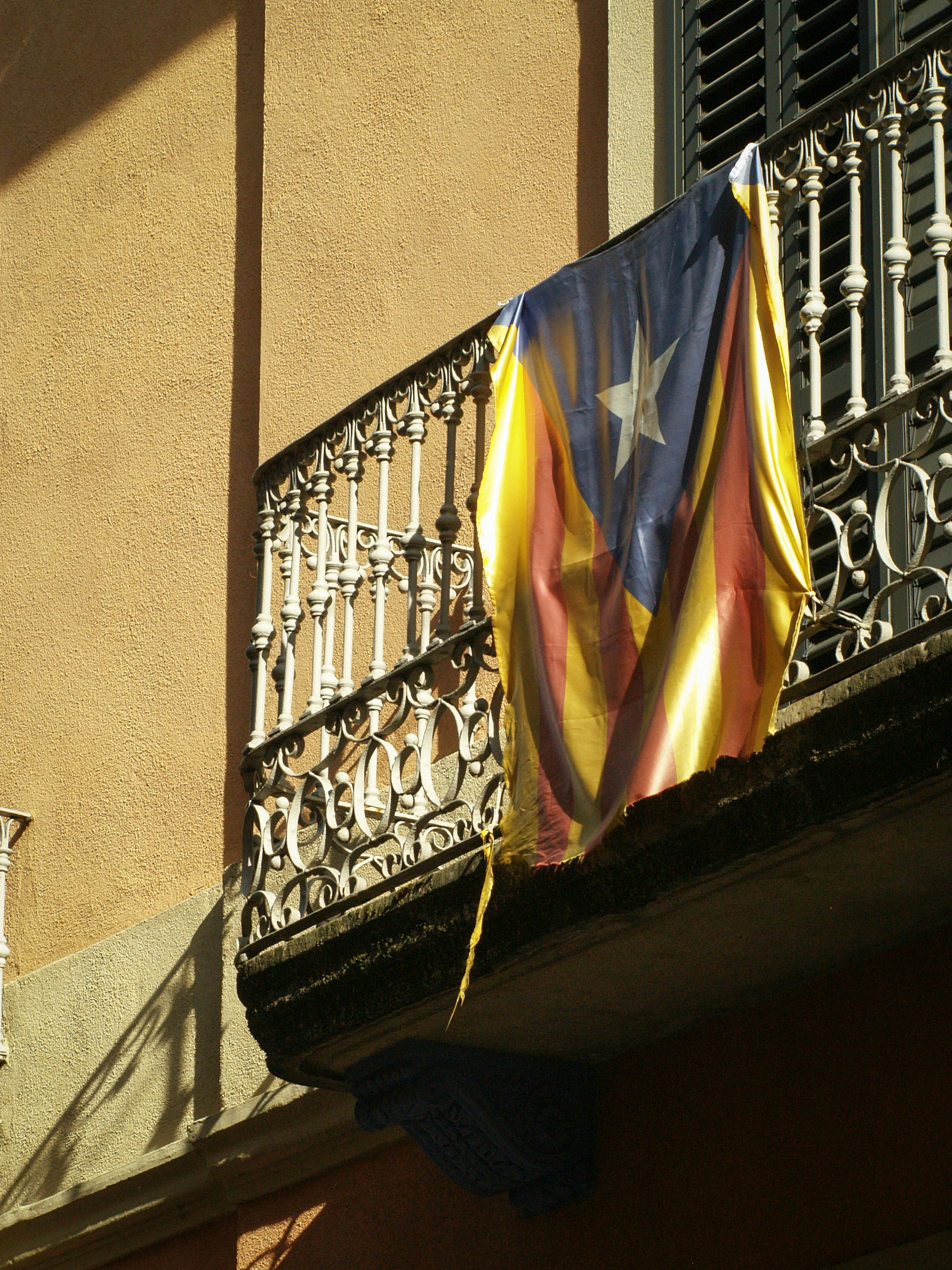 A catalan flag hangs from a wrought iron balcony.