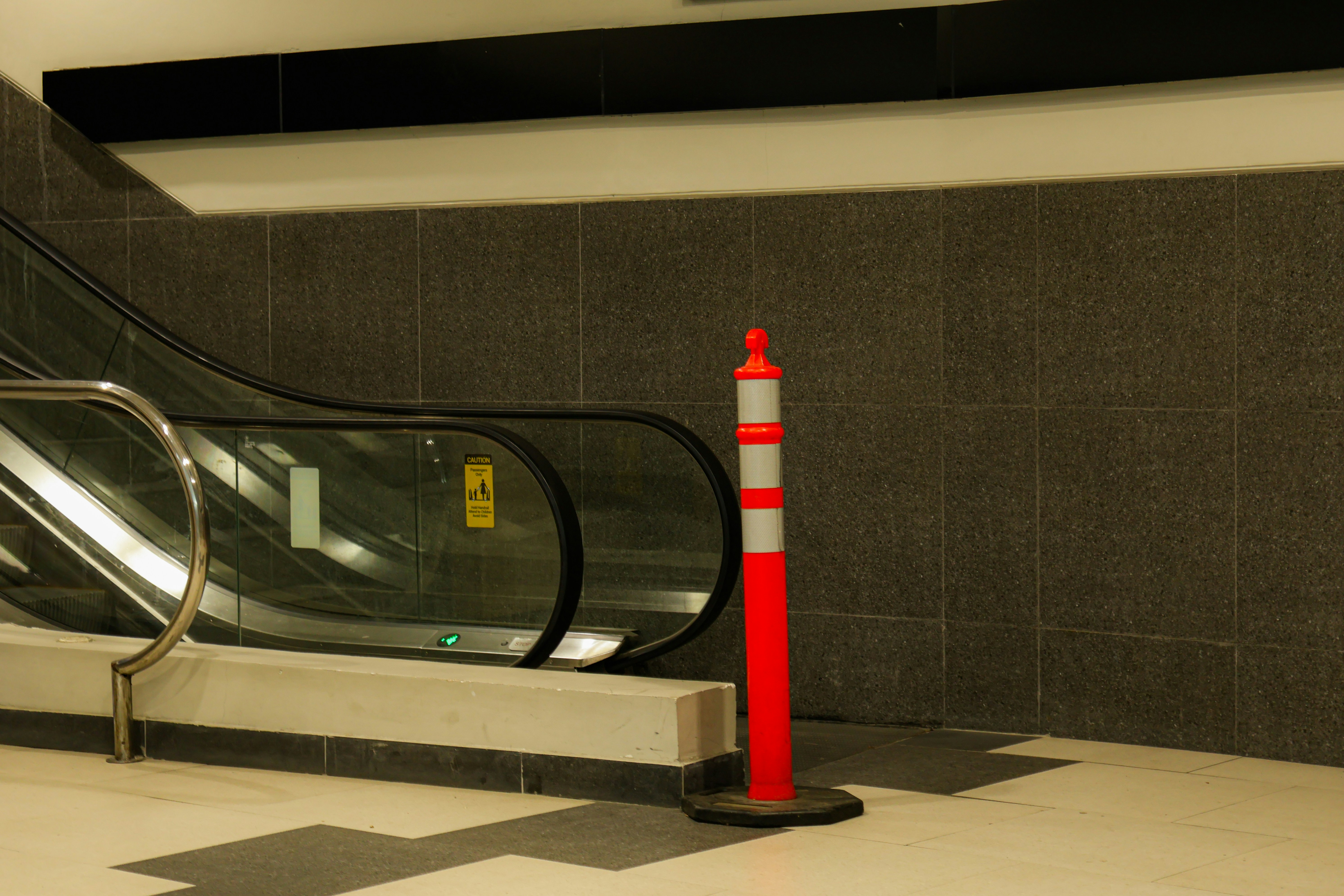 An escalator and a safety cone in a building.