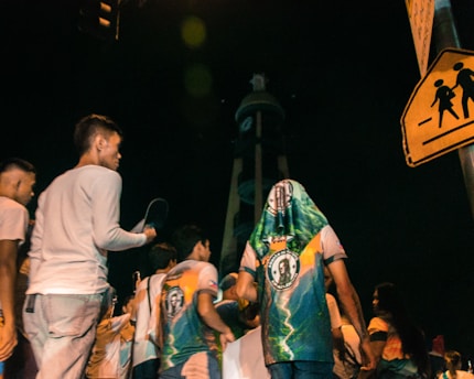People gather around a tower at night.