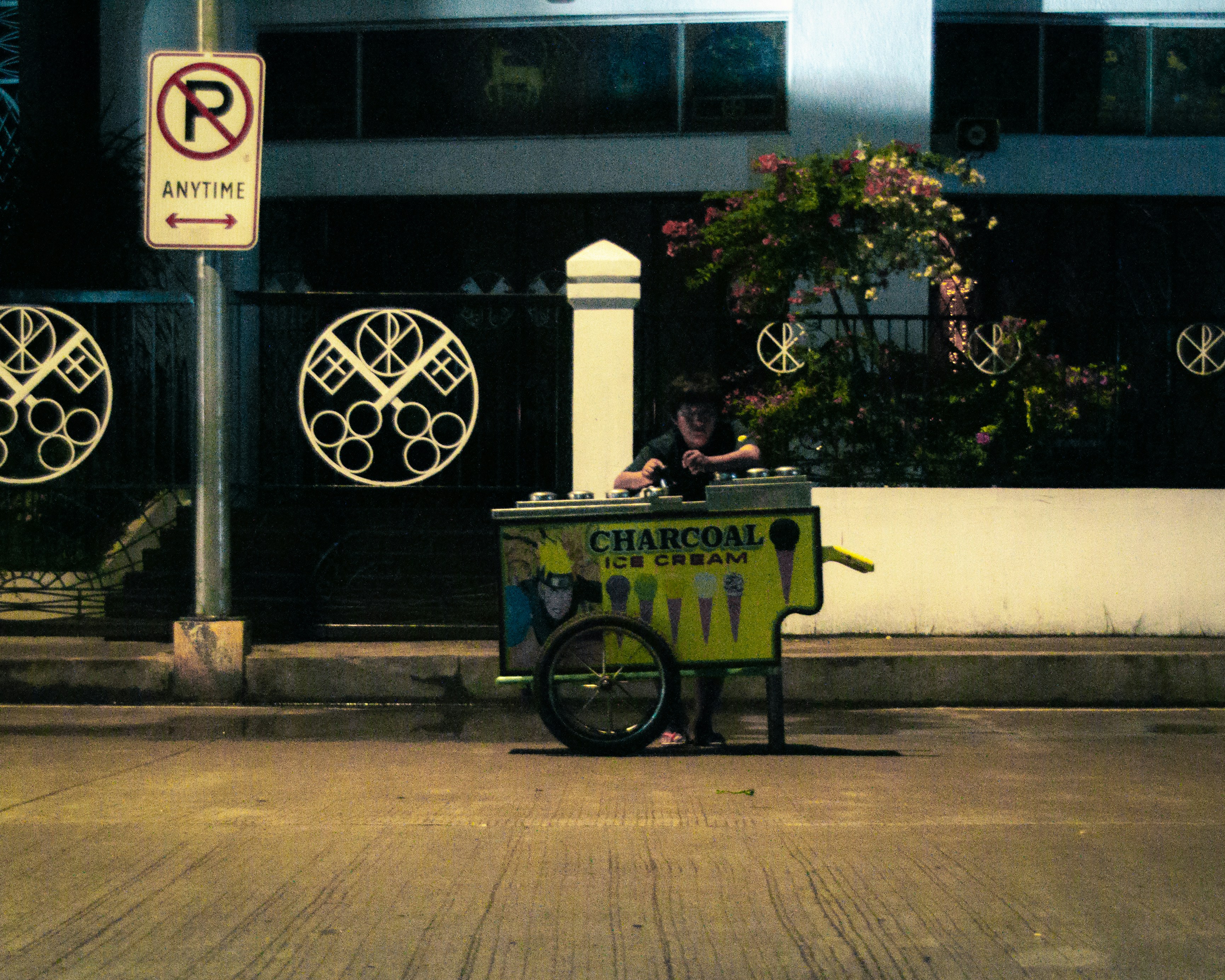An ice cream vendor stands near a "no parking" sign.