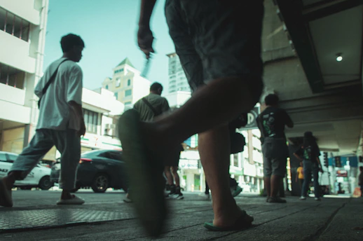 People walk on a city sidewalk in the sunlight