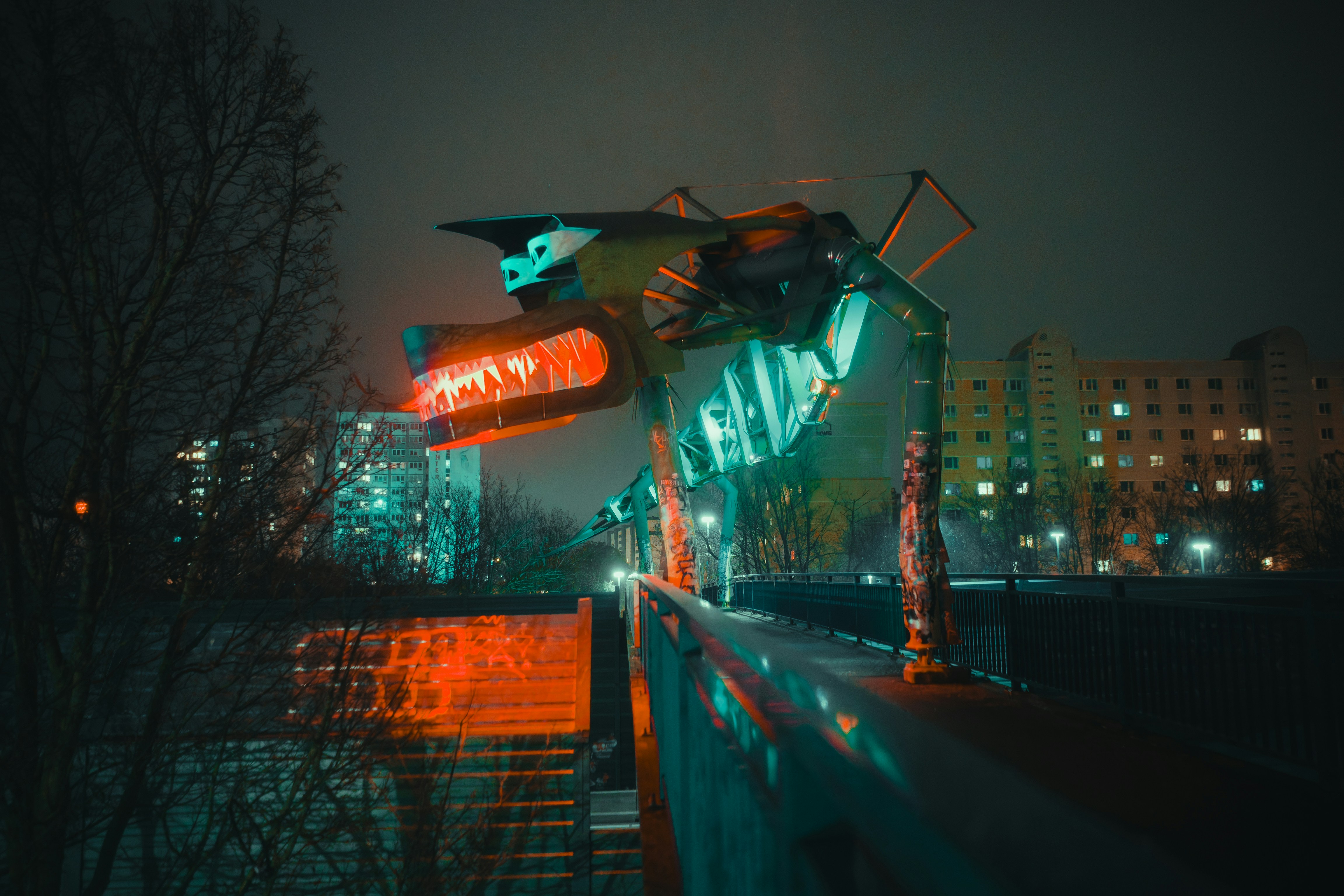 A futuristic structure glows over a city bridge.