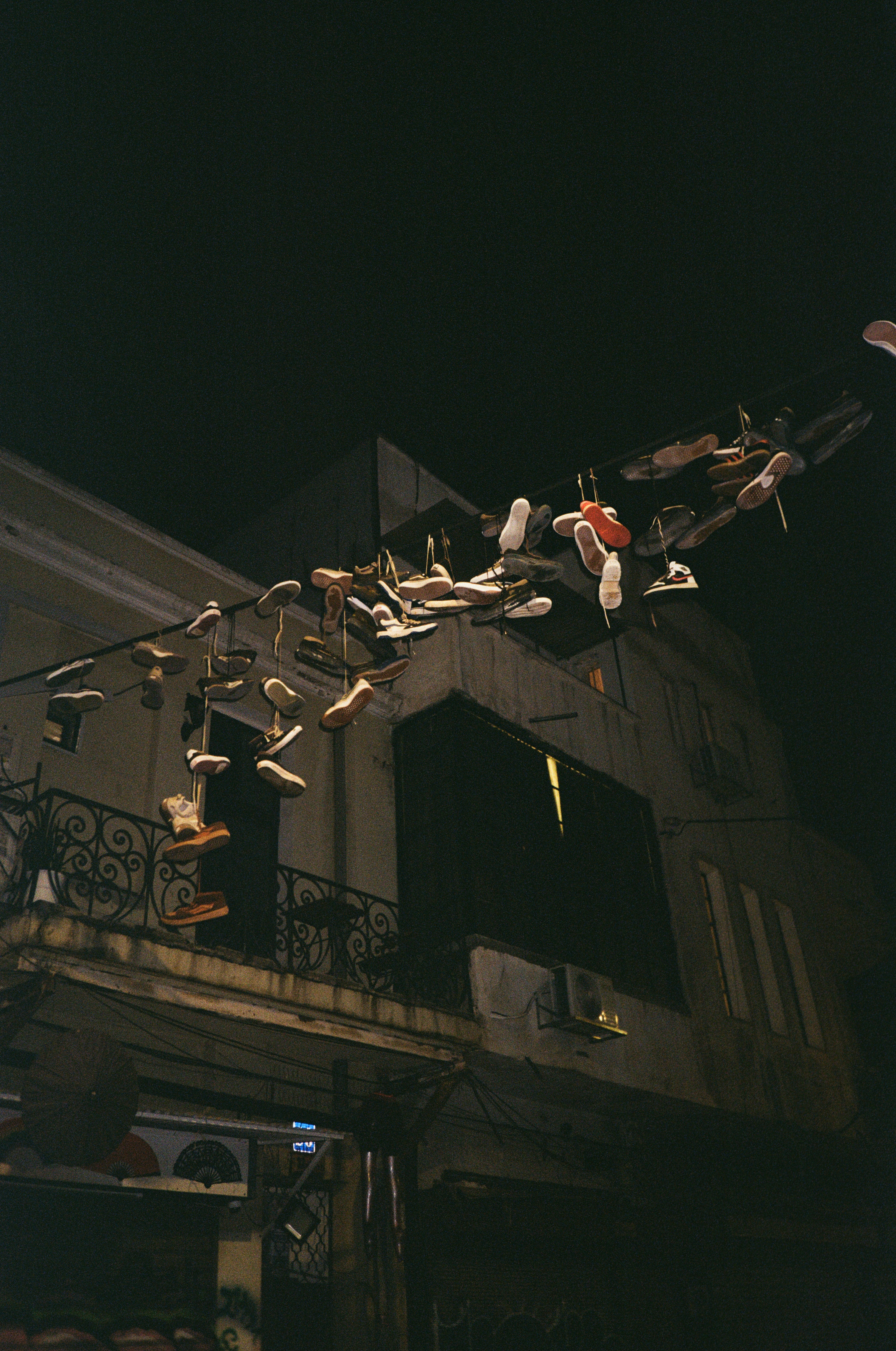 Shoes hang from a wire above a building.