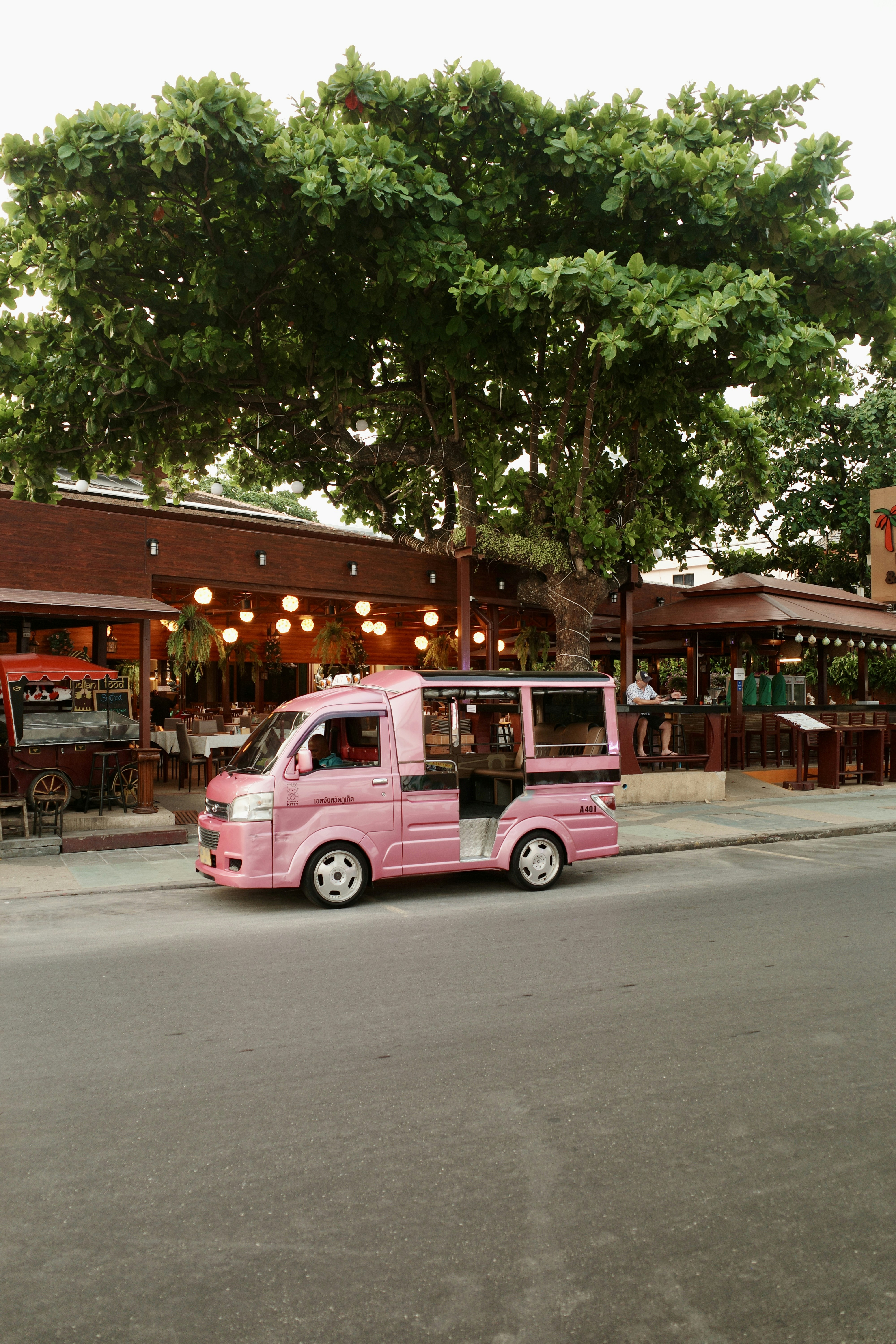 Pink taxi parked in front of a restaurant.