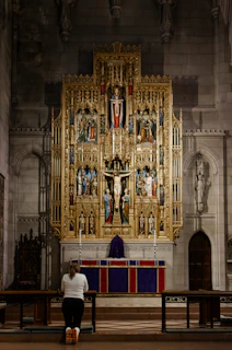 A person prays before a church altar.