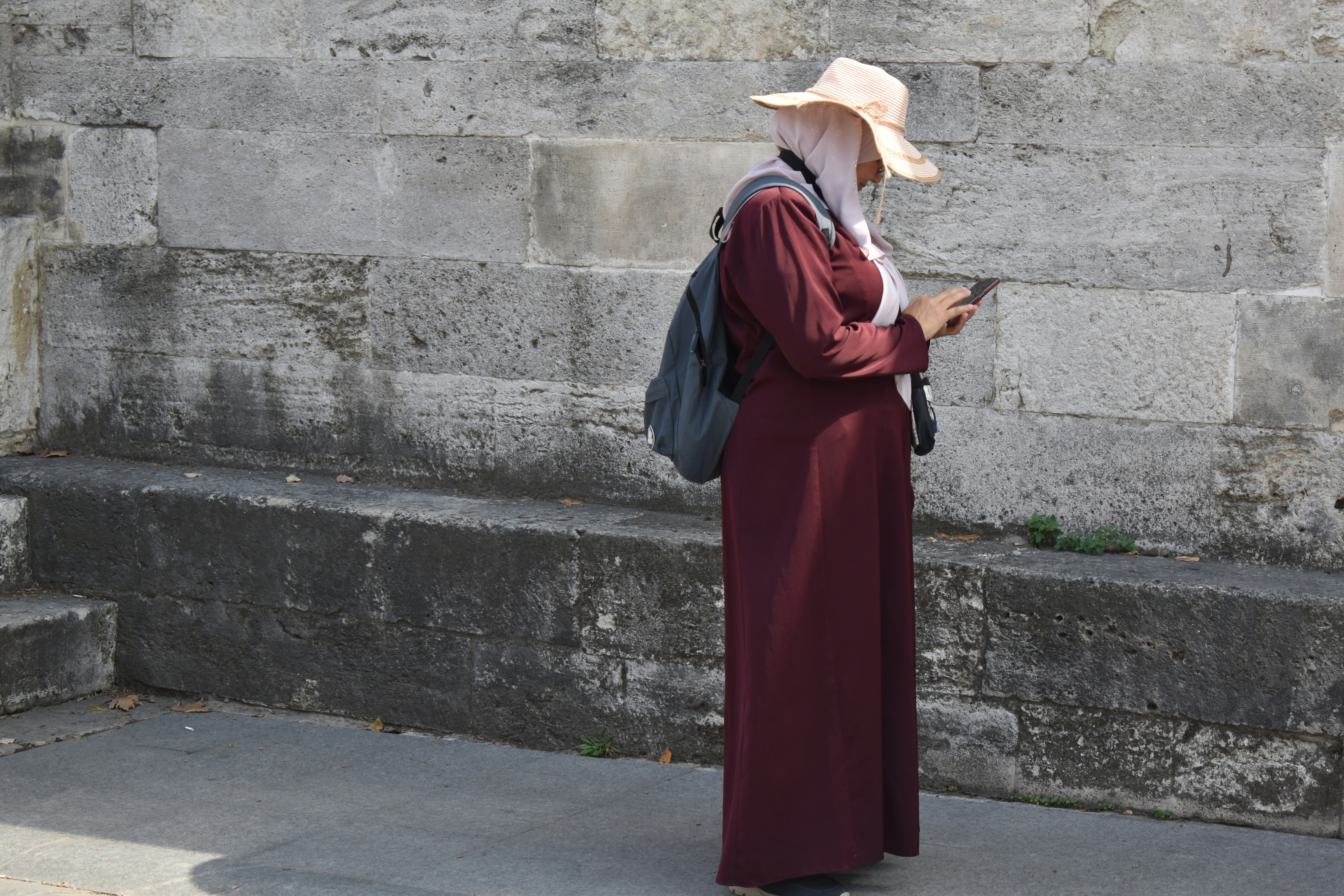 Woman using smartphone at stone wall