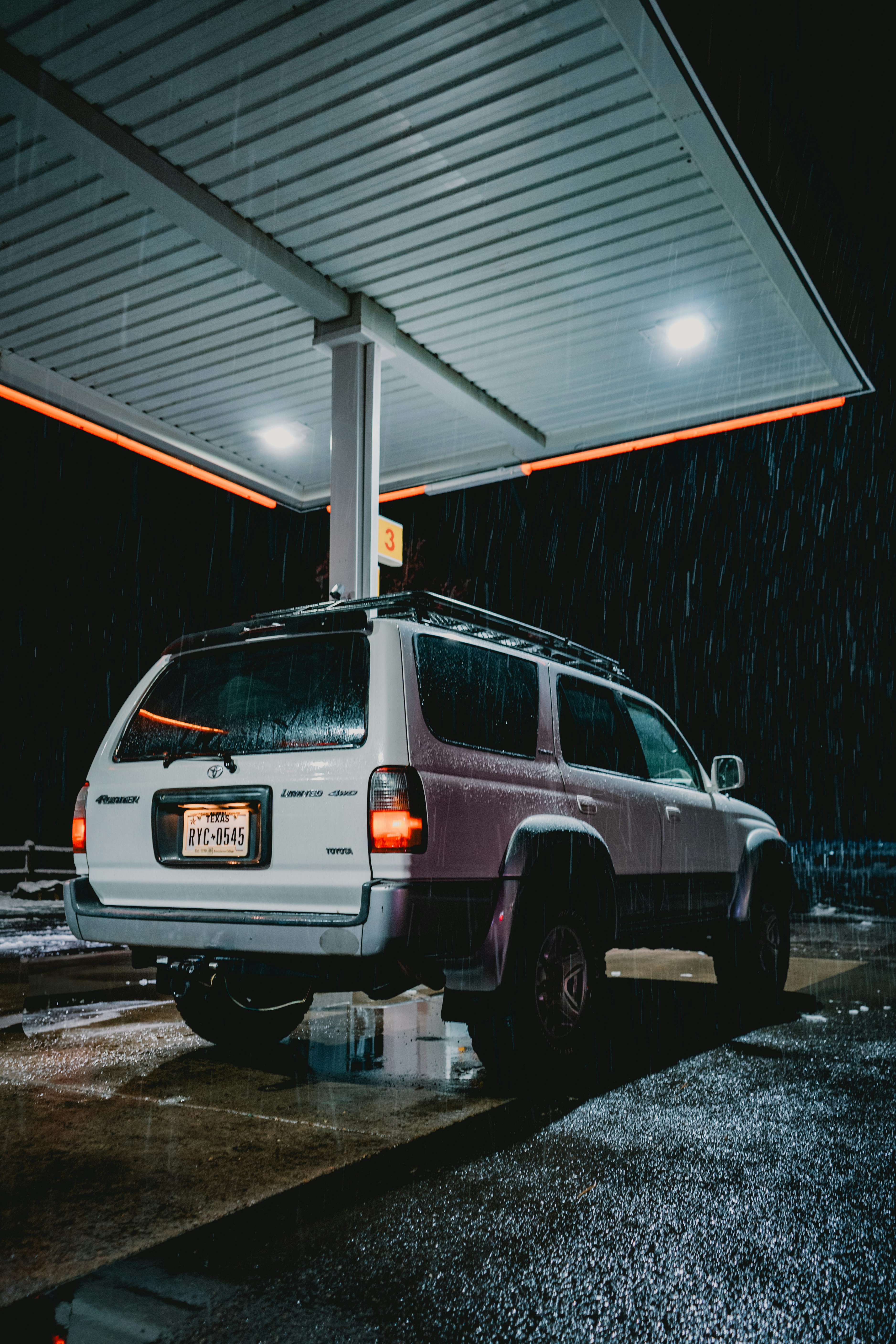 Ein SUV wird bei Regen an einer Tankstelle abgestellt.