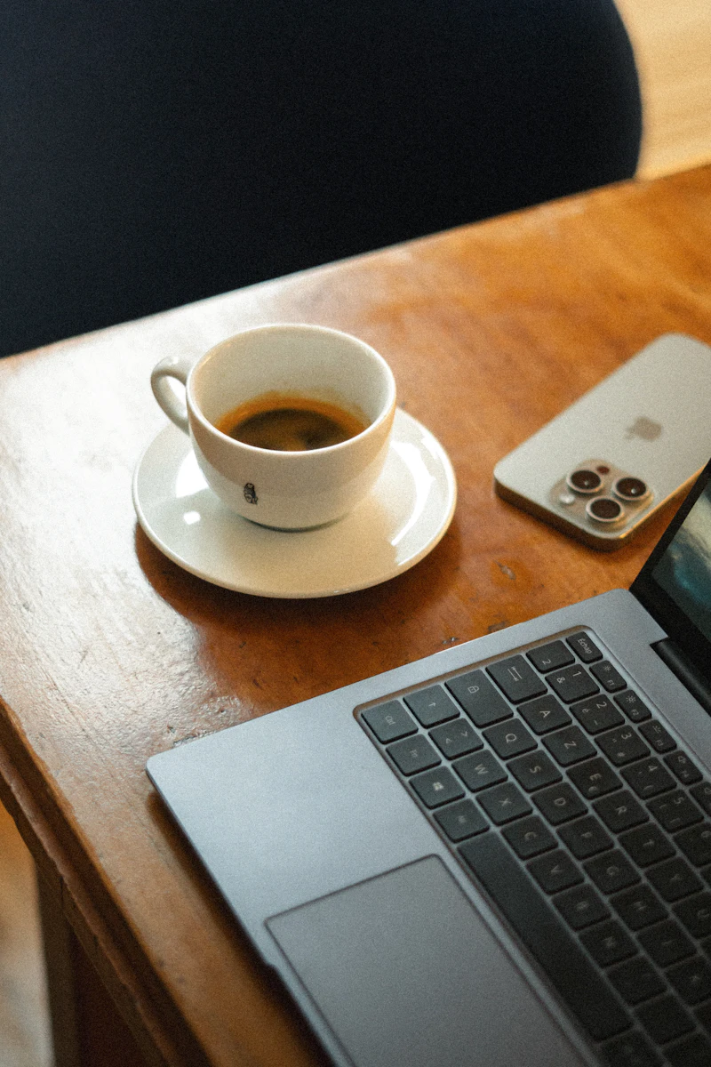 Mesa de madeira com café, celular e notebook