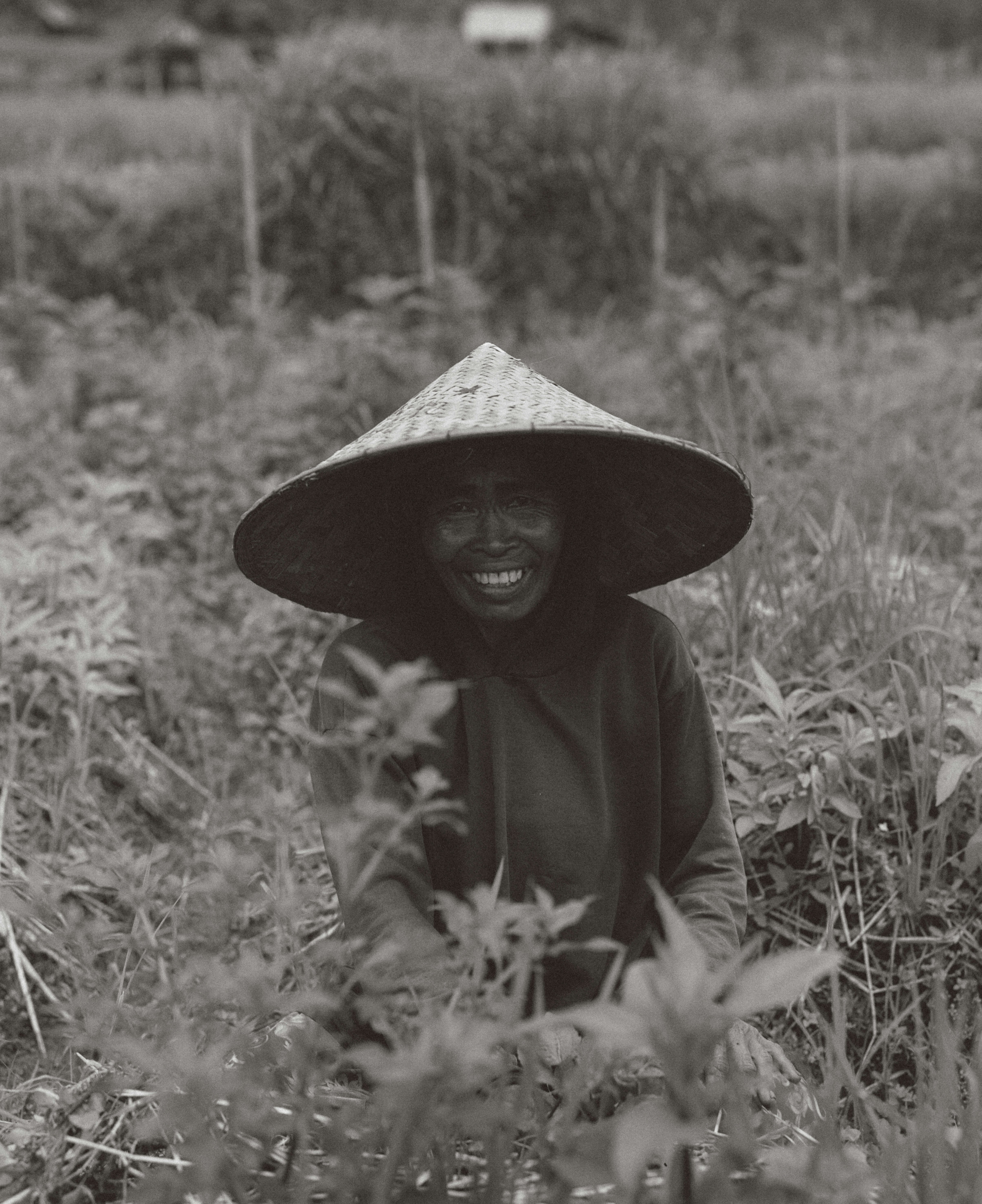 A woman smiles wearing a conical hat.
