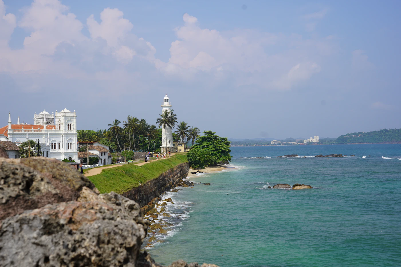 The white lighthouse of Galle Fort standing above coral ramparts and the Indian Ocean on Sri Lanka's southern coast at golden hour