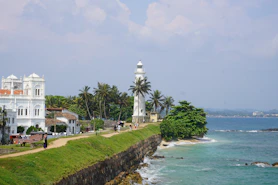 A lighthouse and buildings overlook the ocean.