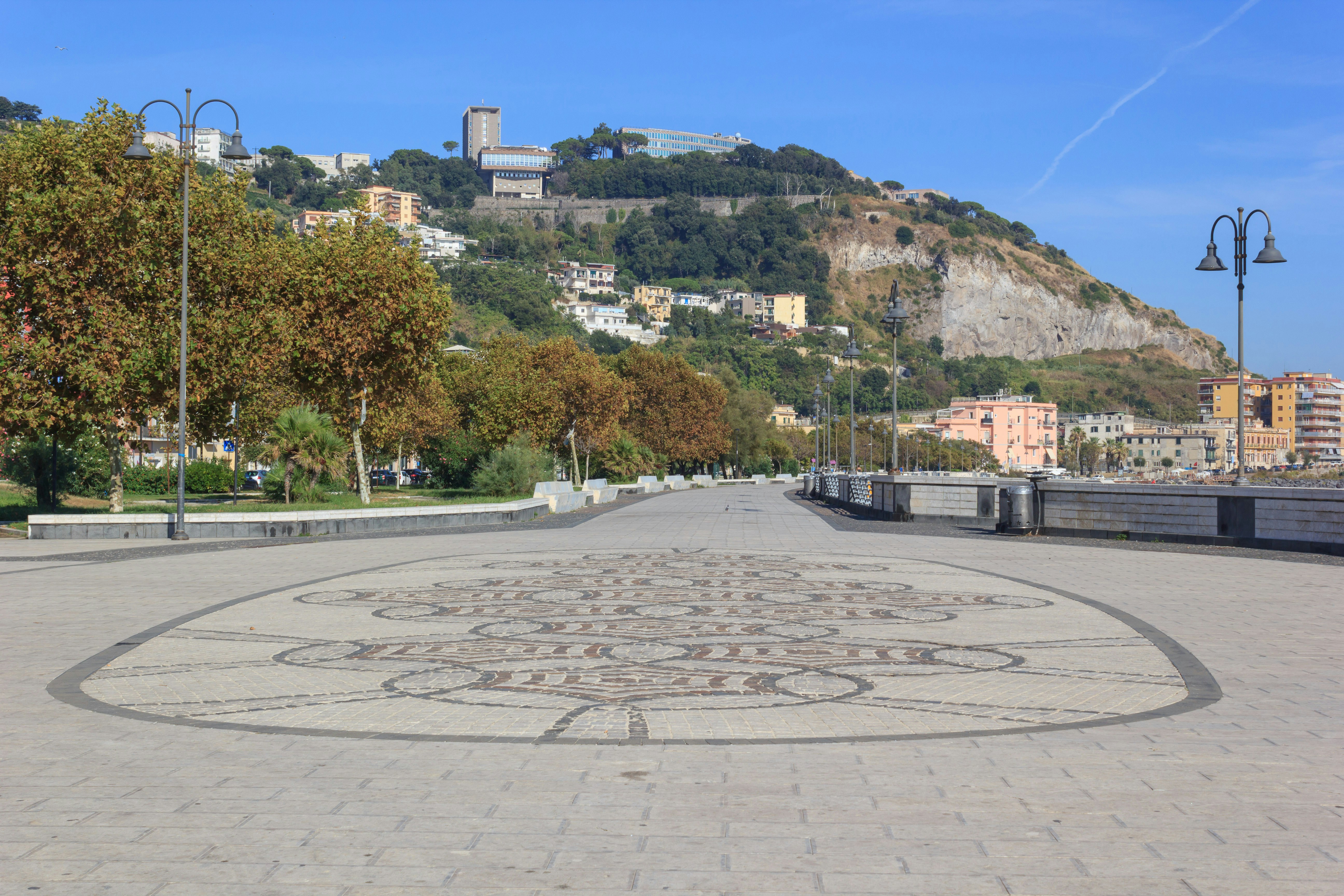 A promenade leads to a hilltop building.