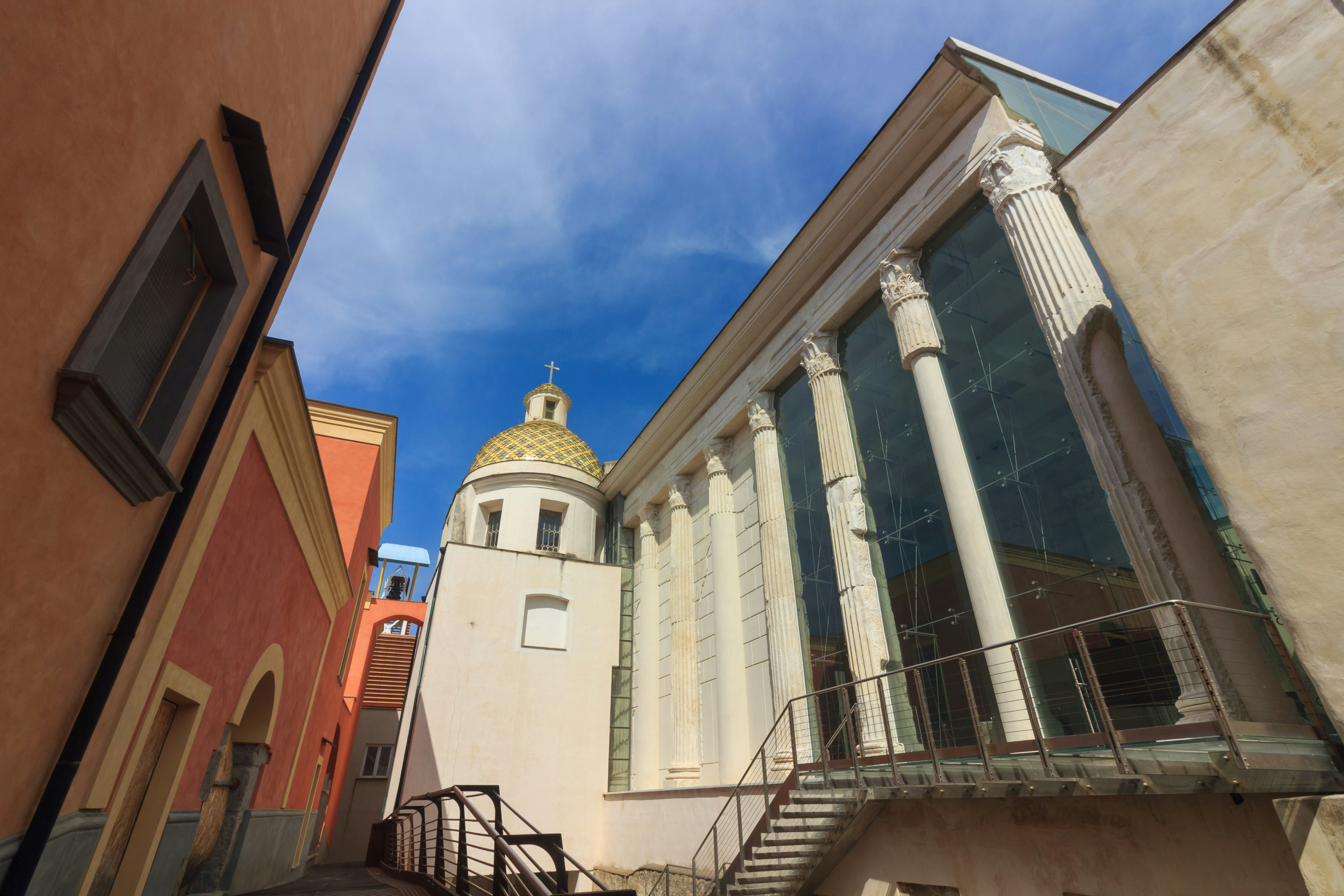 A church is seen between buildings on a sunny day.