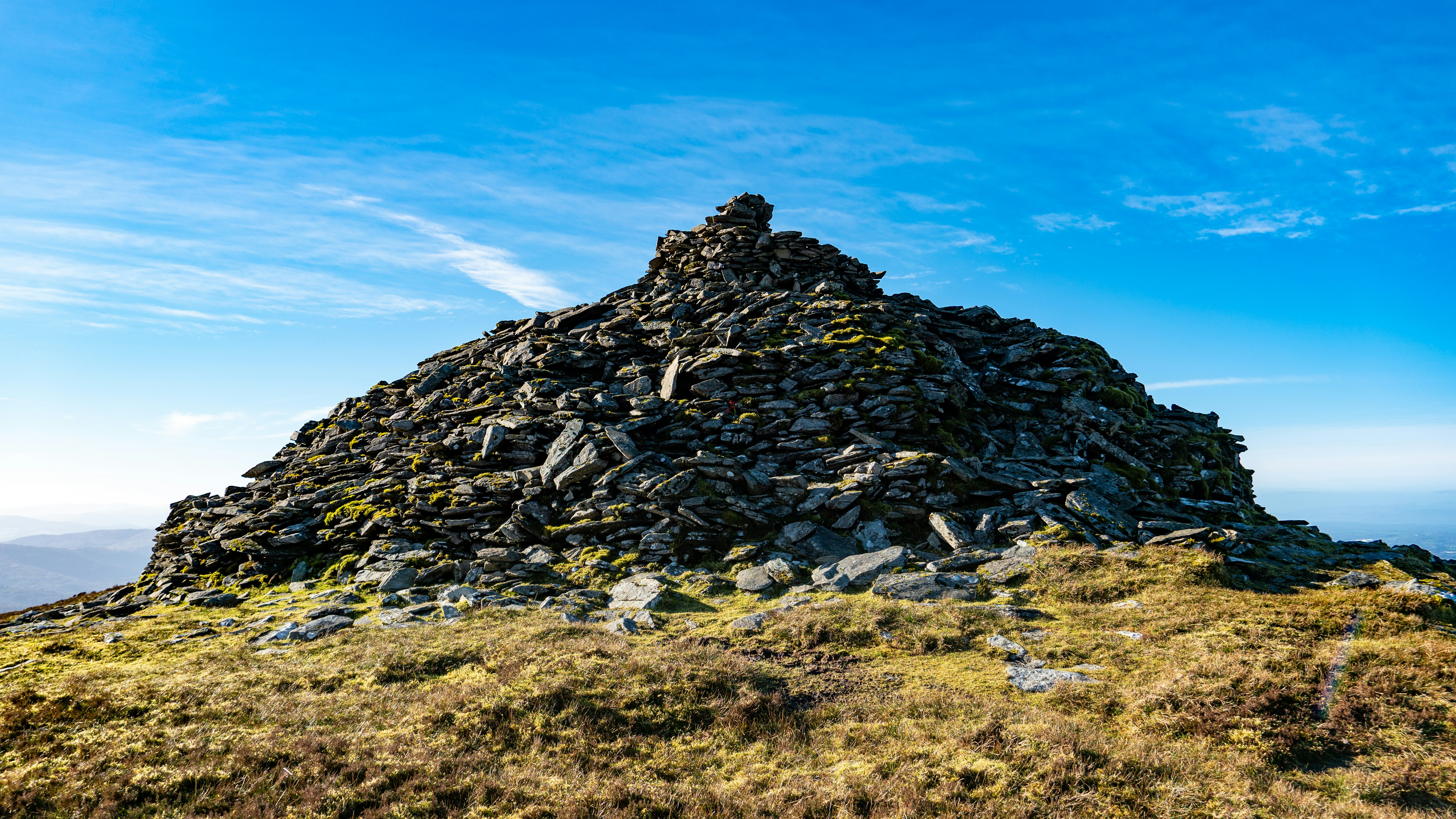 A stone cairn stands atop a mountain.