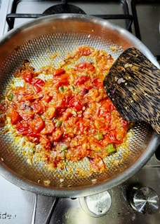 Tomatoes and spices are cooking in a pan.