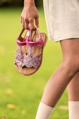 Girl holds sparkly pink sandals in her hand.