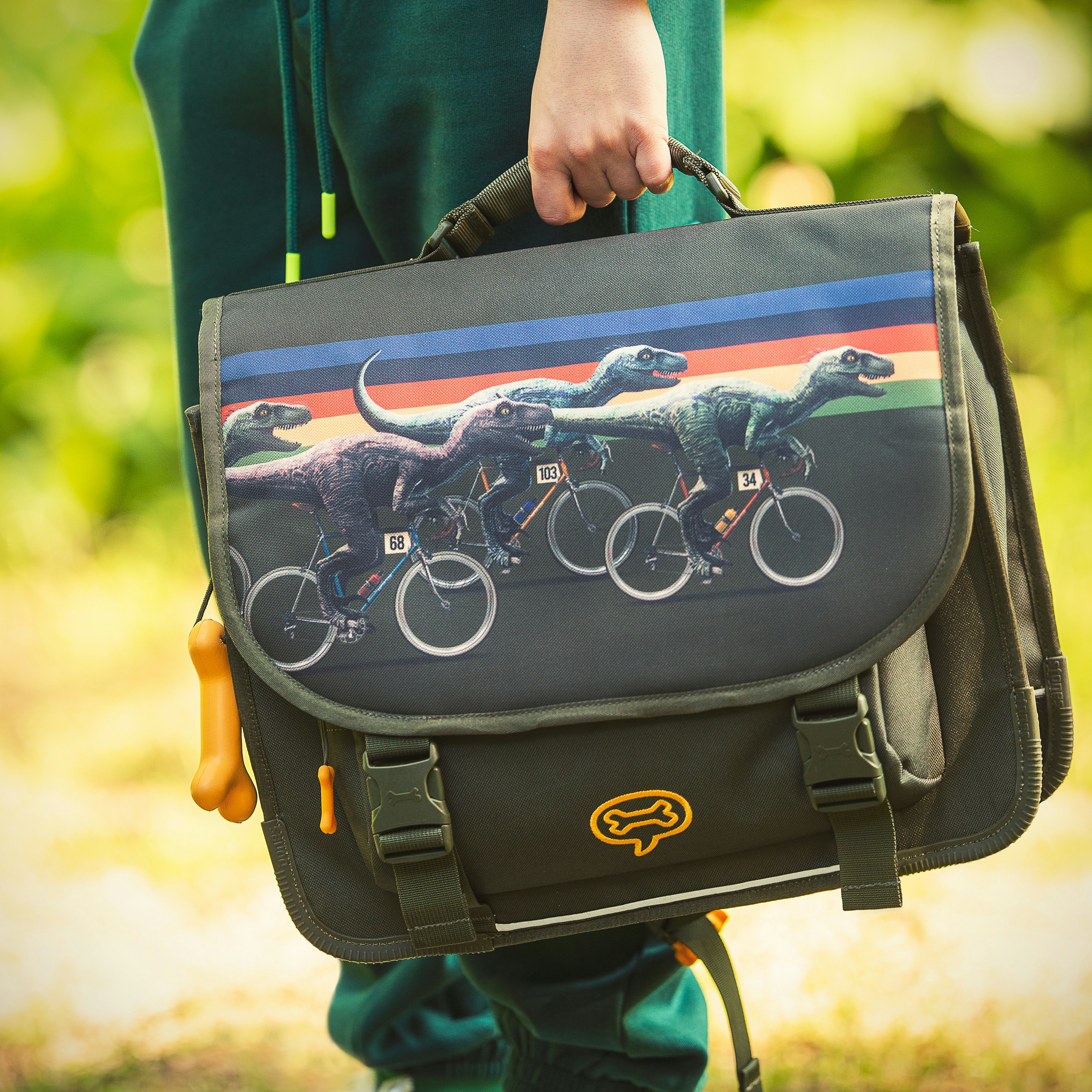A child holds a dinosaur-themed backpack.