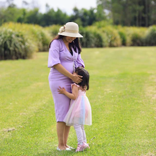 Pregnant woman embraces her young child.