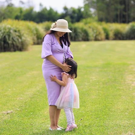 Pregnant woman embraces her young child.