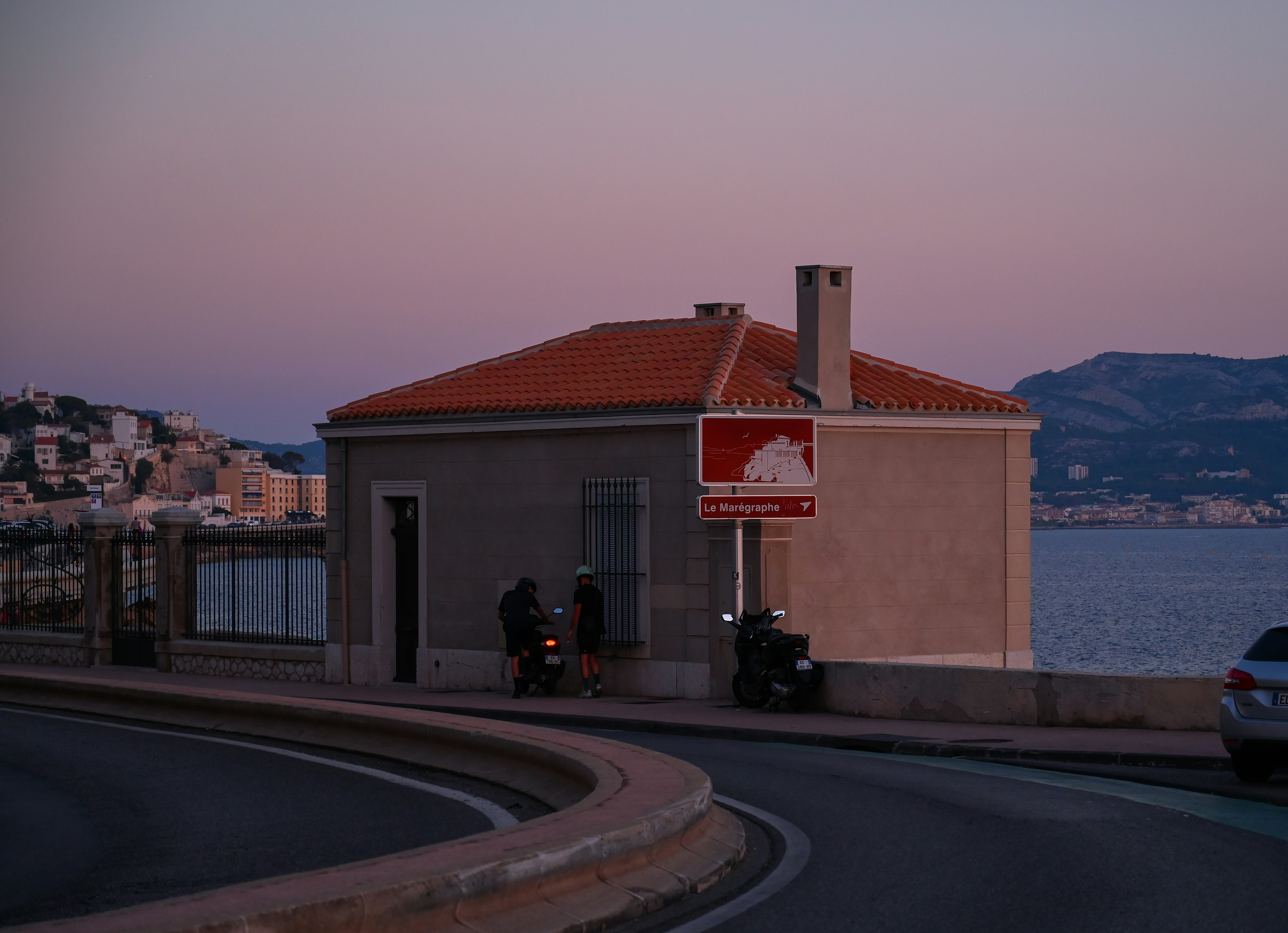 A small building sits by the water at dusk.