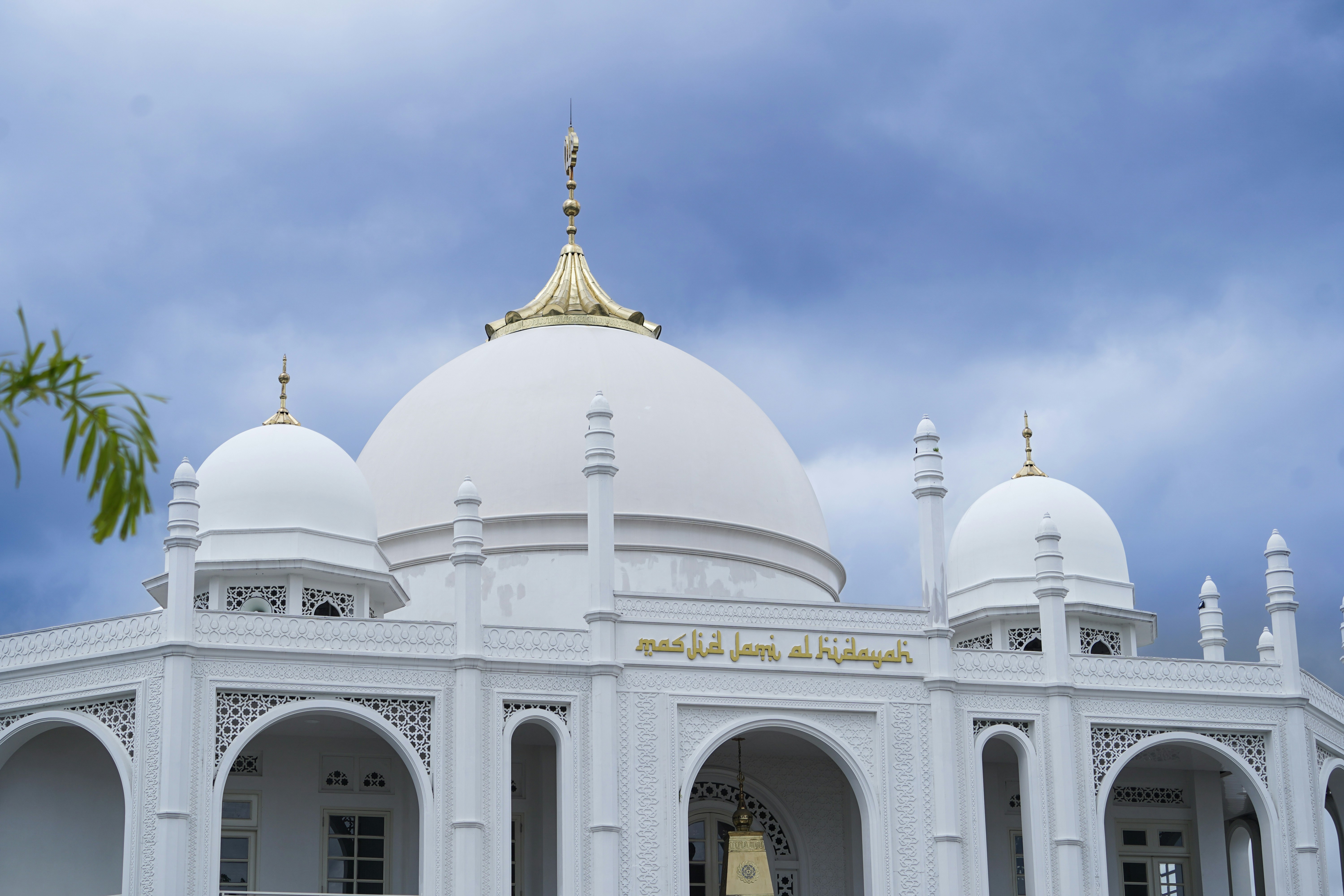 White mosque with a domed roof against cloudy sky.