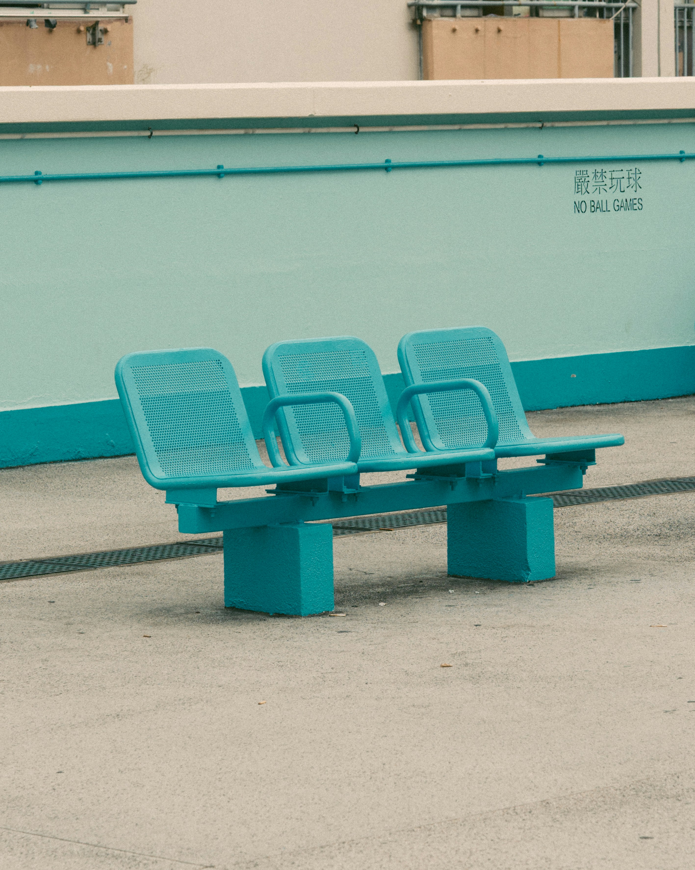 A teal bench sits in front of a blue wall.