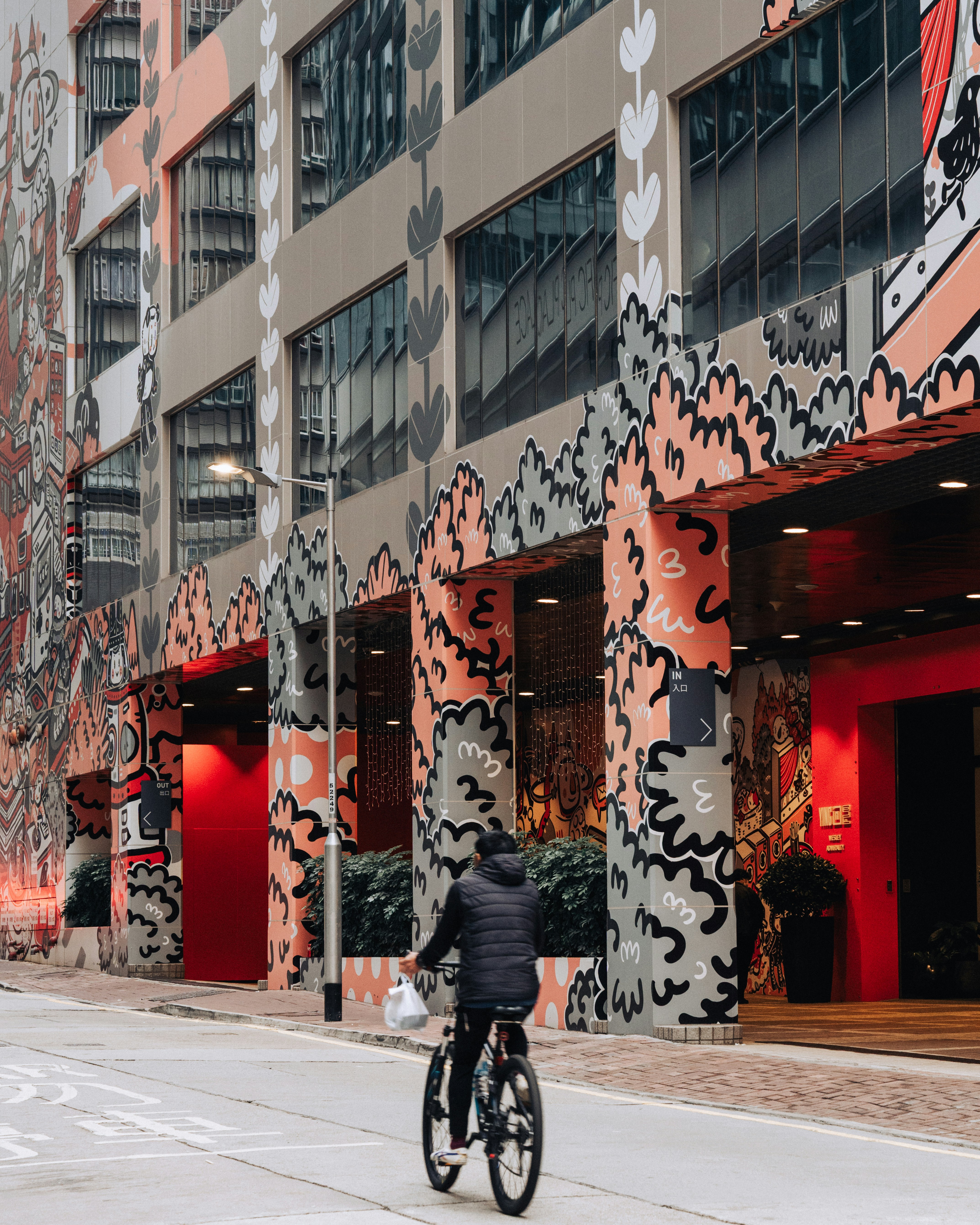 Ein Radfahrer fährt an der Fassade eines bunten Gebäudes vorbei.